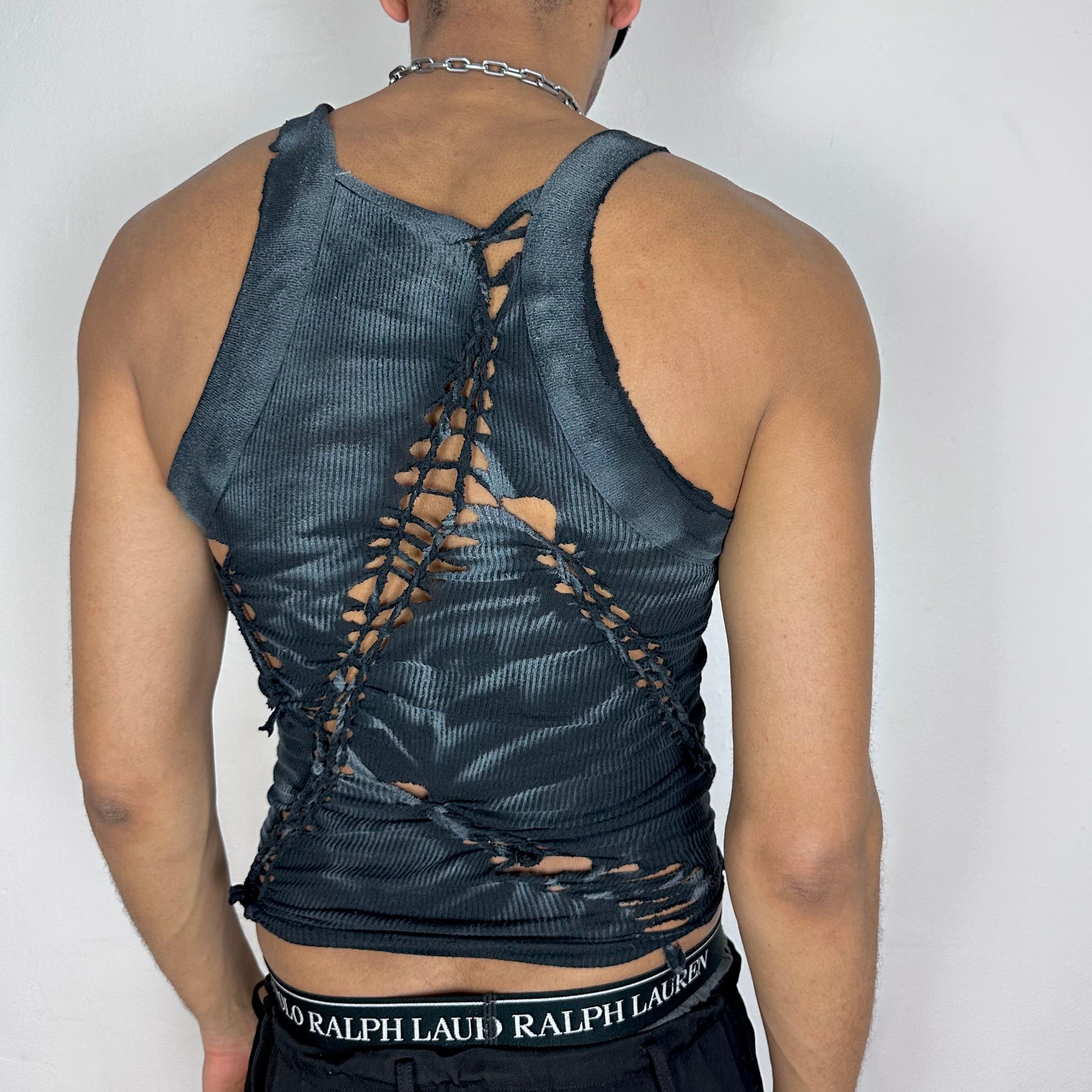 ASTROBOI* 'Magus' black and white G-Unit braided Y2K tank top, rear view showing braid, slash, and white paint accent construction, worn by male model.