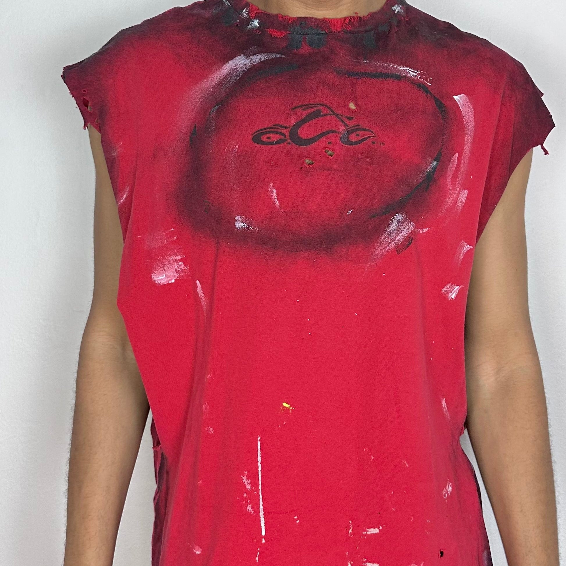 Close-up of ASTROBOI* Orange County Choppers tank showing black airbrush detailing, white and black paint splatter, and distressed finish on red fabric.