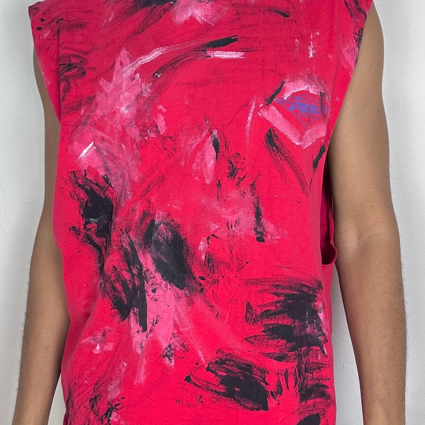 Close-up of ASTROBOI* 'Hobie' showing white and black paint splatter detail and technicolor Hobie logo on red fabric.