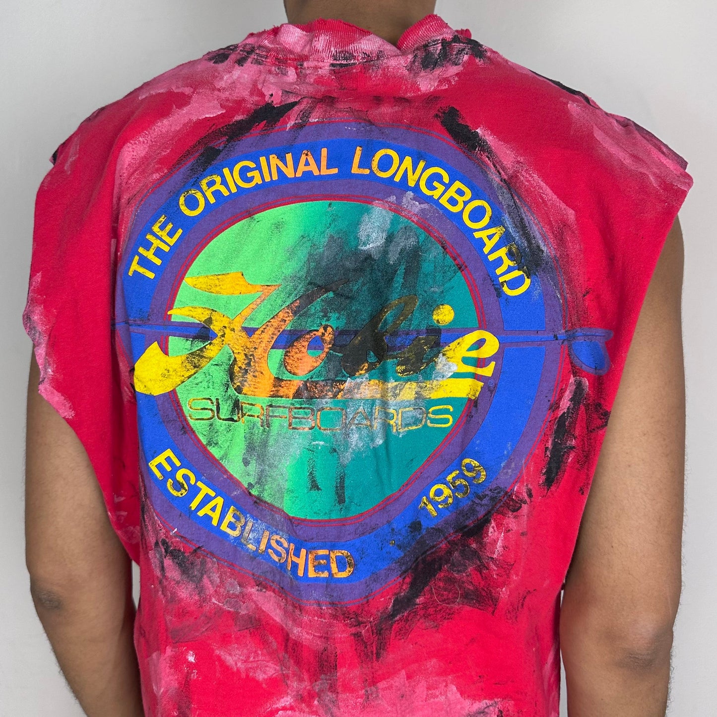 Person wearing a red sleeveless shirt with a colorful graphic design on the back, against a plain background.