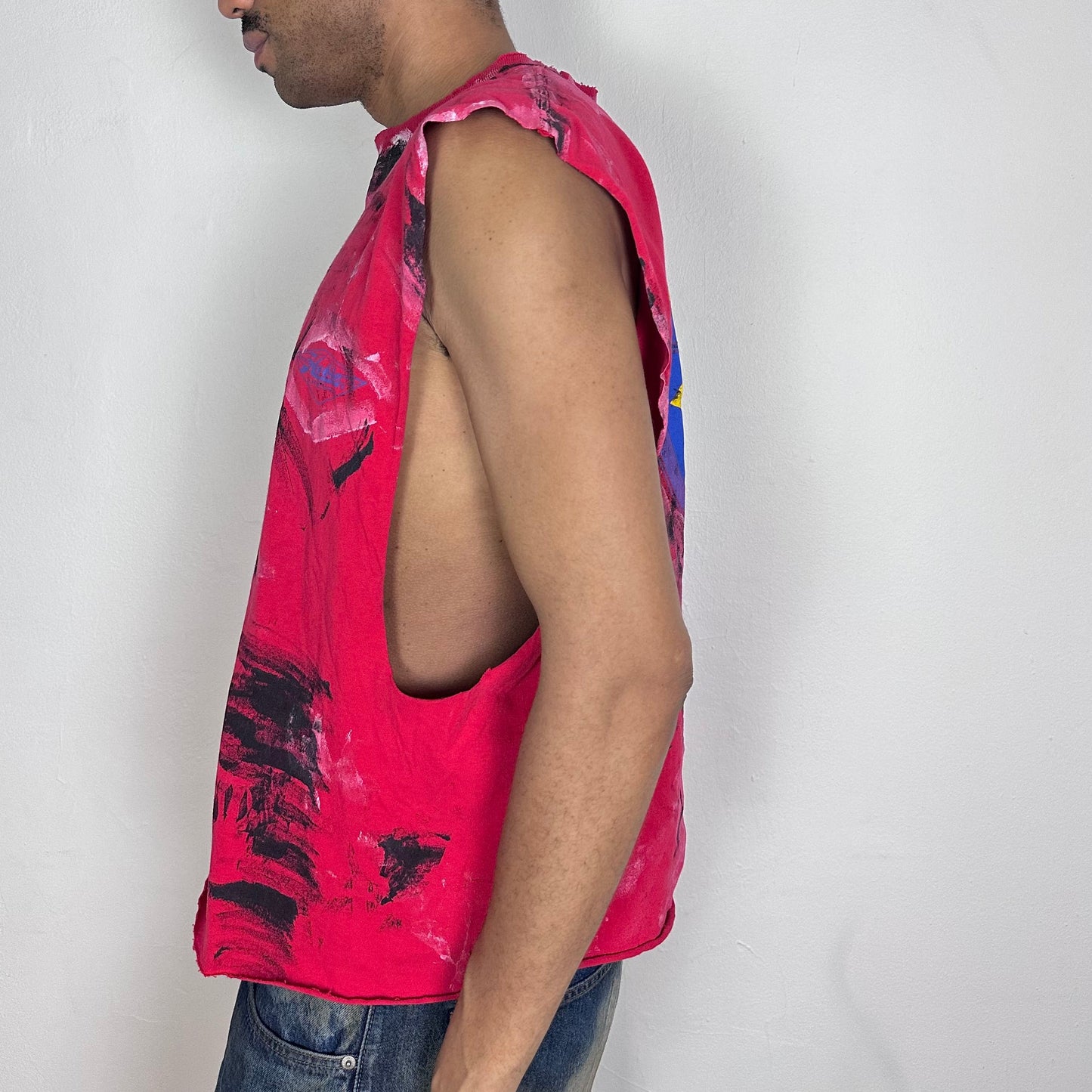 Left side detail of ASTROBOI* 'Hobie' showing paint splatter detail and raw hem construction on red graphic tee.