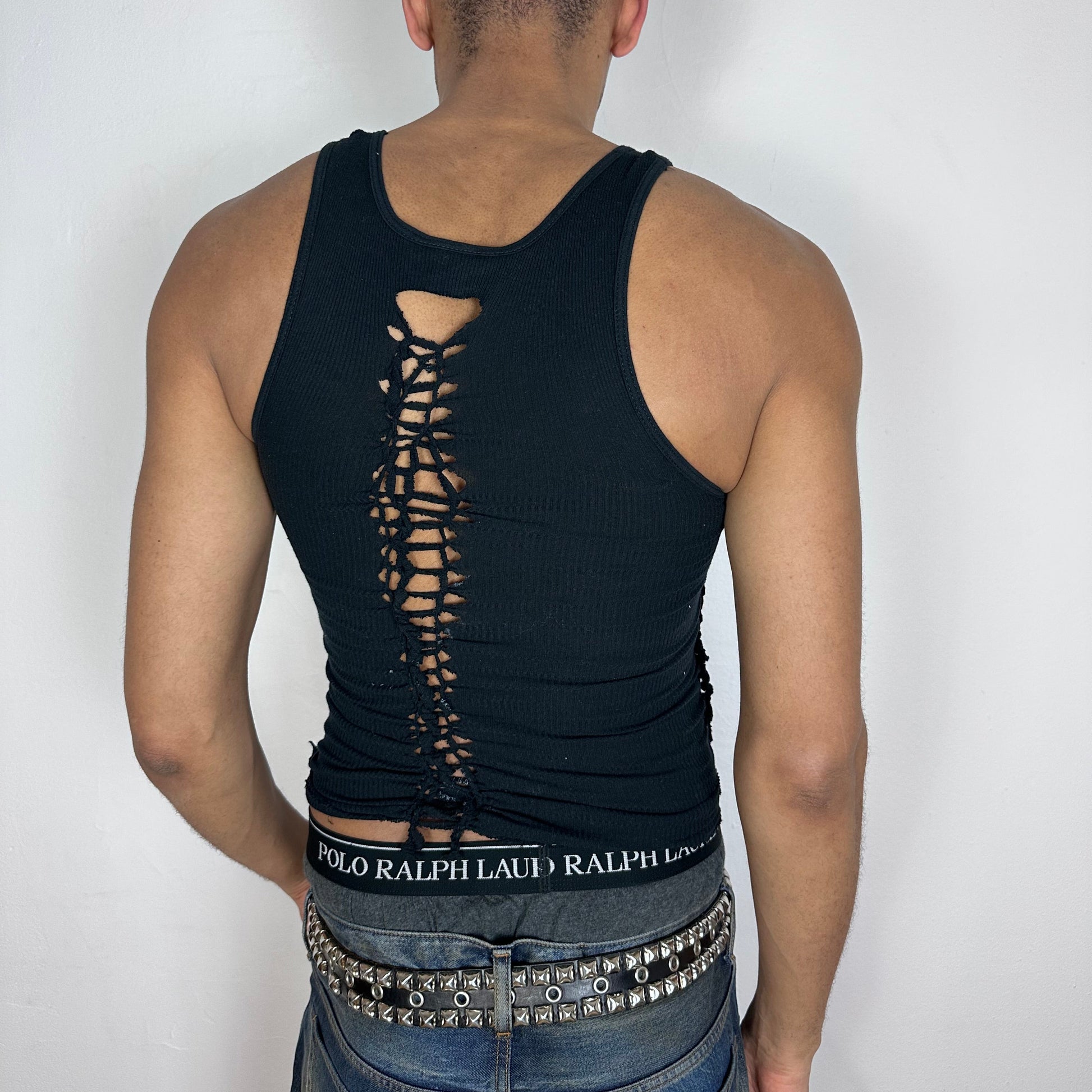 ASTROBOI* 'Shadow Play' black braided twist tank top, rear view showing braid and cut-out construction with paint splatter detail, worn by male model.