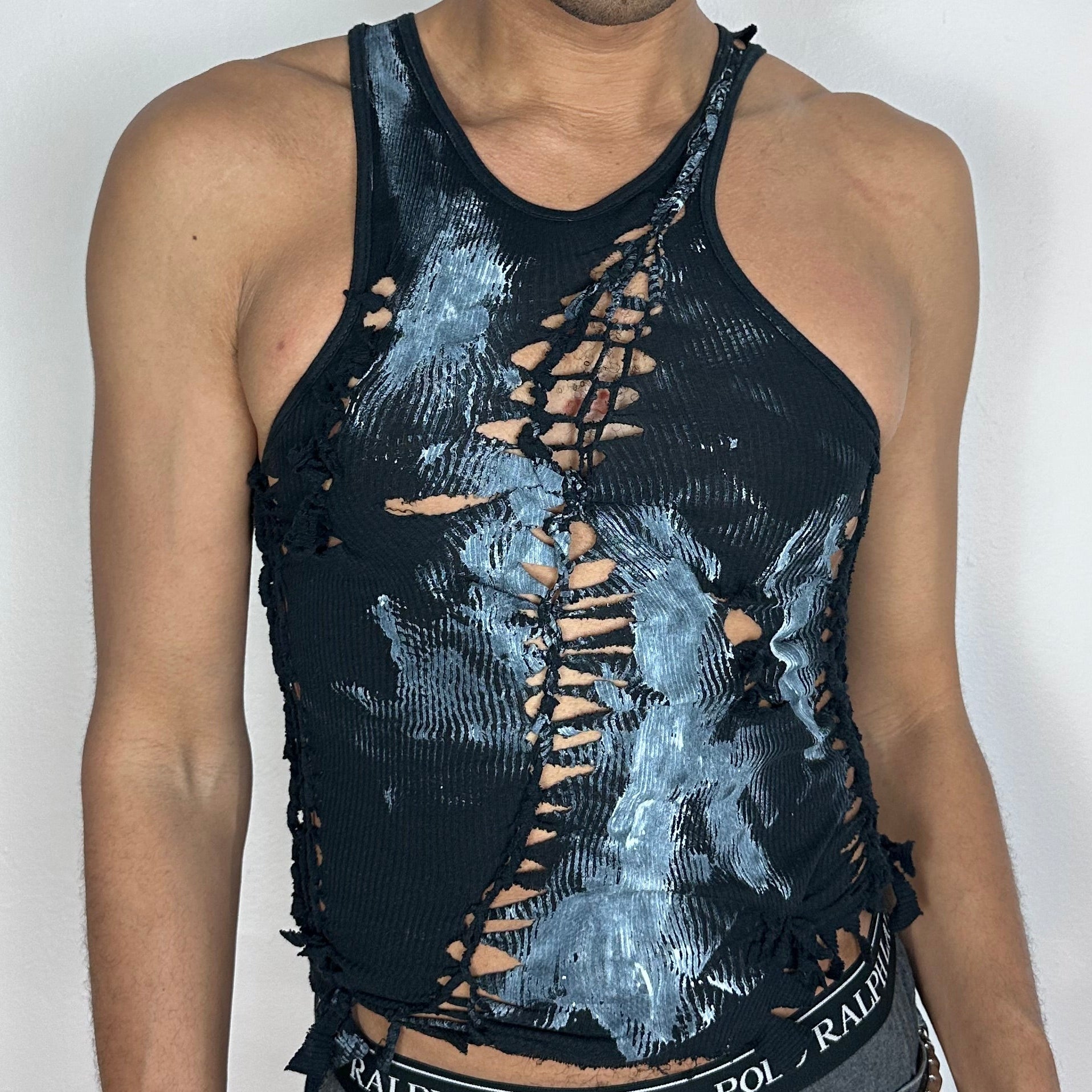 Close-up of ASTROBOI* 'Shadow Play' showing black hand-braided texture, cut-out detailing, and white paint splatter contrast on body.