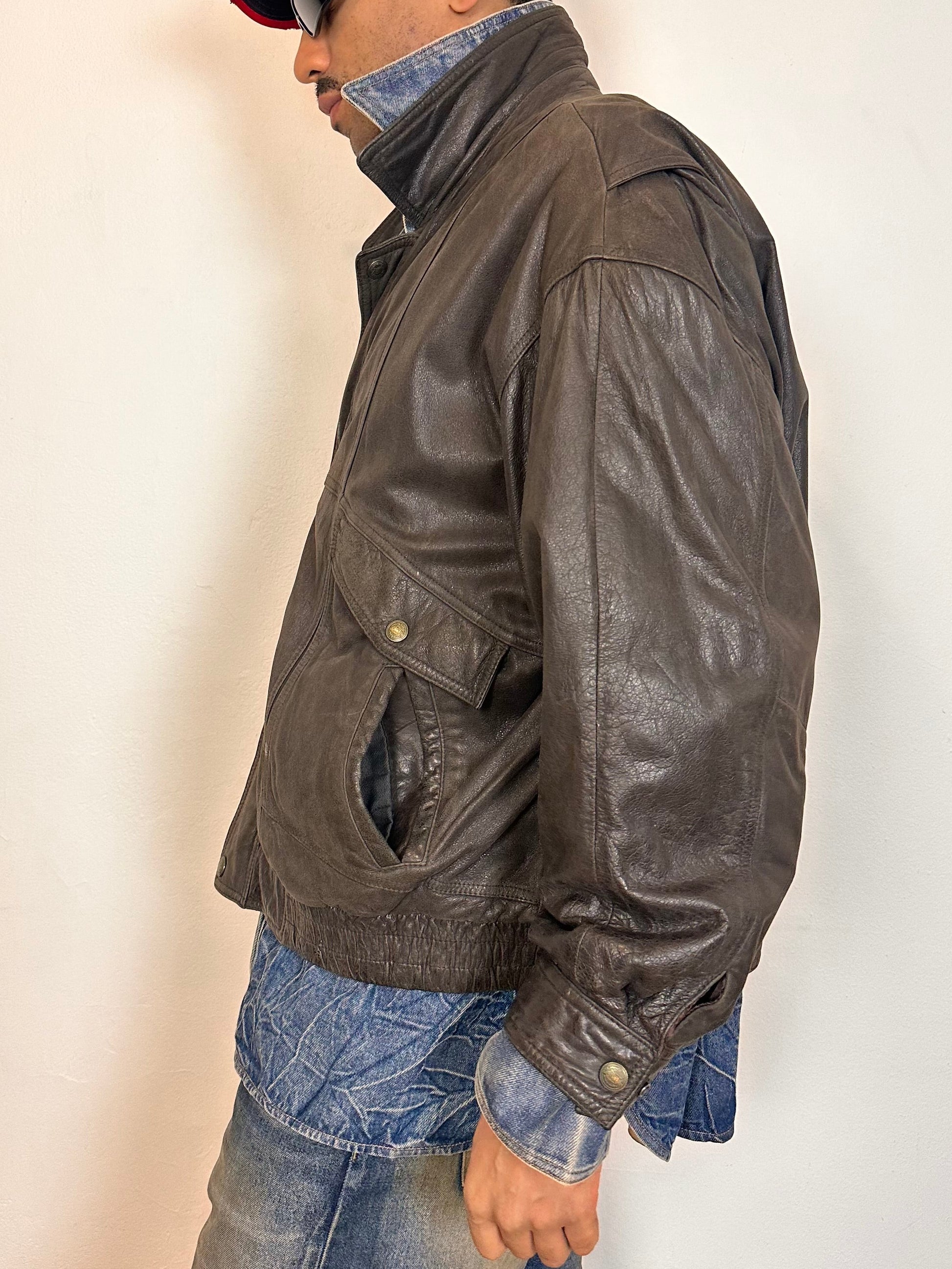 Left side of Vintage Canton Ridge brown leather bomber jacket with ribbed cuffs, elastic hem, relaxed fit, and multiple pockets, fits like XL.