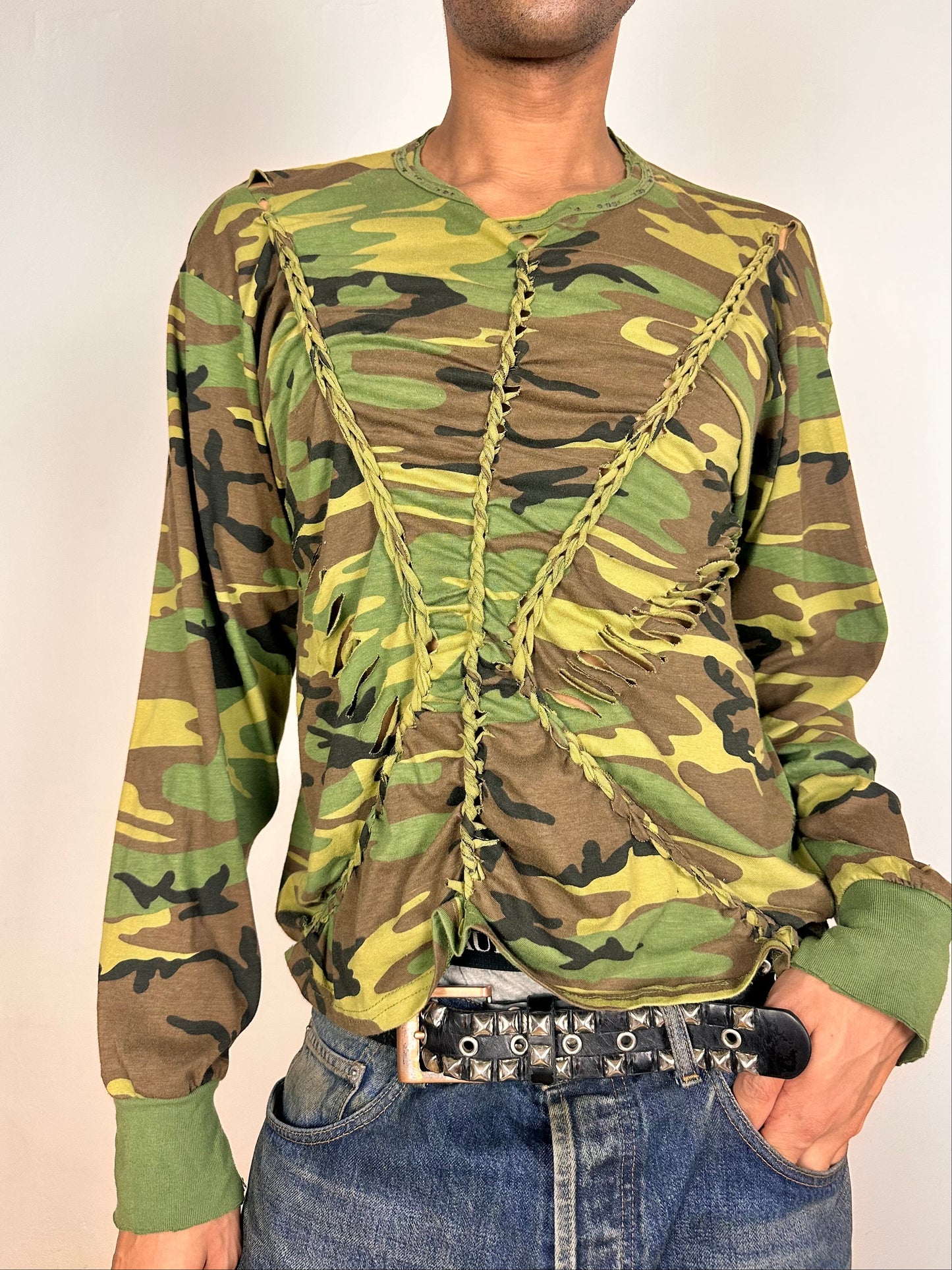 Front of ASTROBOI* green camouflage T-shirt with braided detailing, tonal rhinestone collar, raw hem, and loose fit, handmade in NYC.