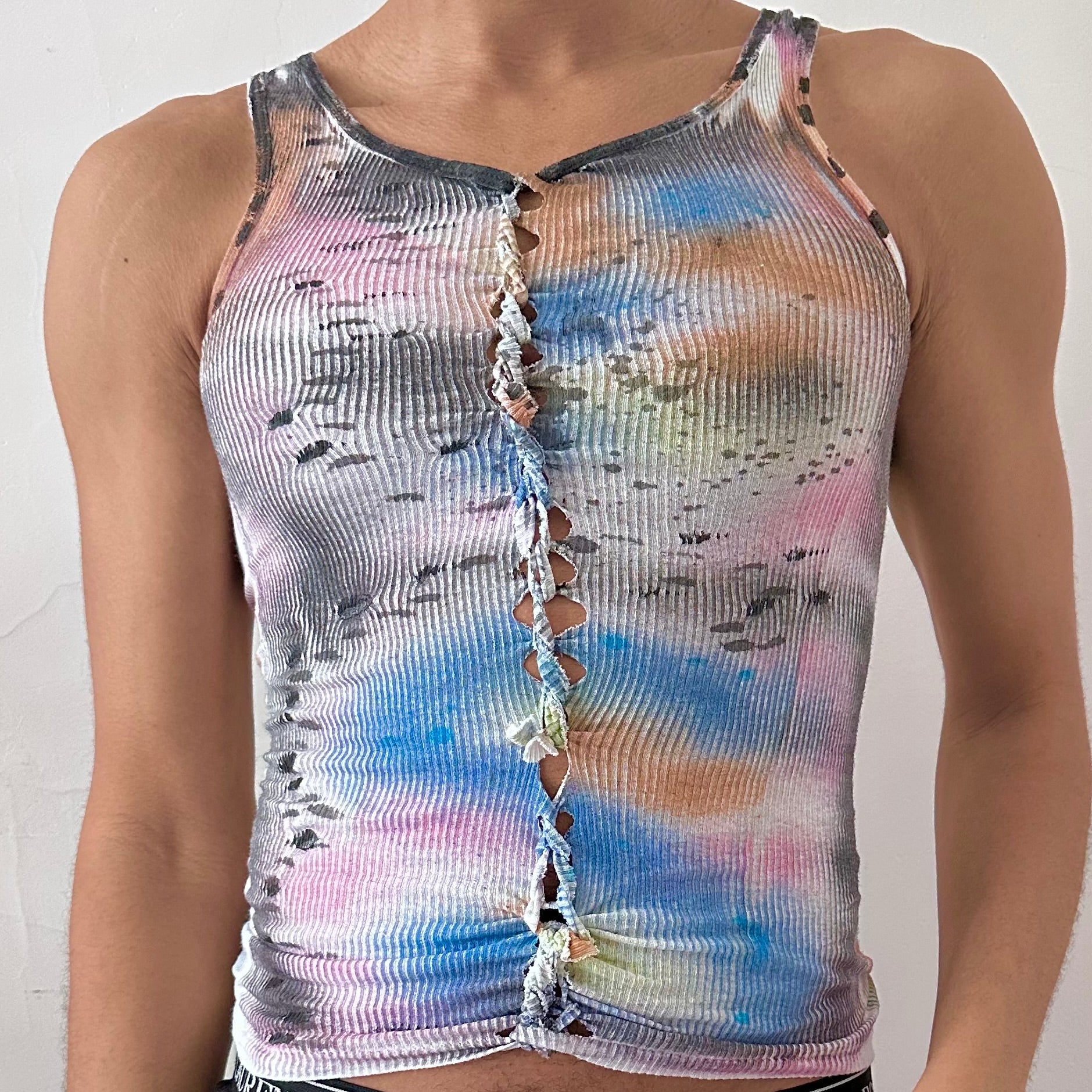 Close-up of ASTROBOI* x Hanes 'Counting Crows' showing hand-braided construction and blue slithery design with multicolored paint clouds on white cotton fabric.
