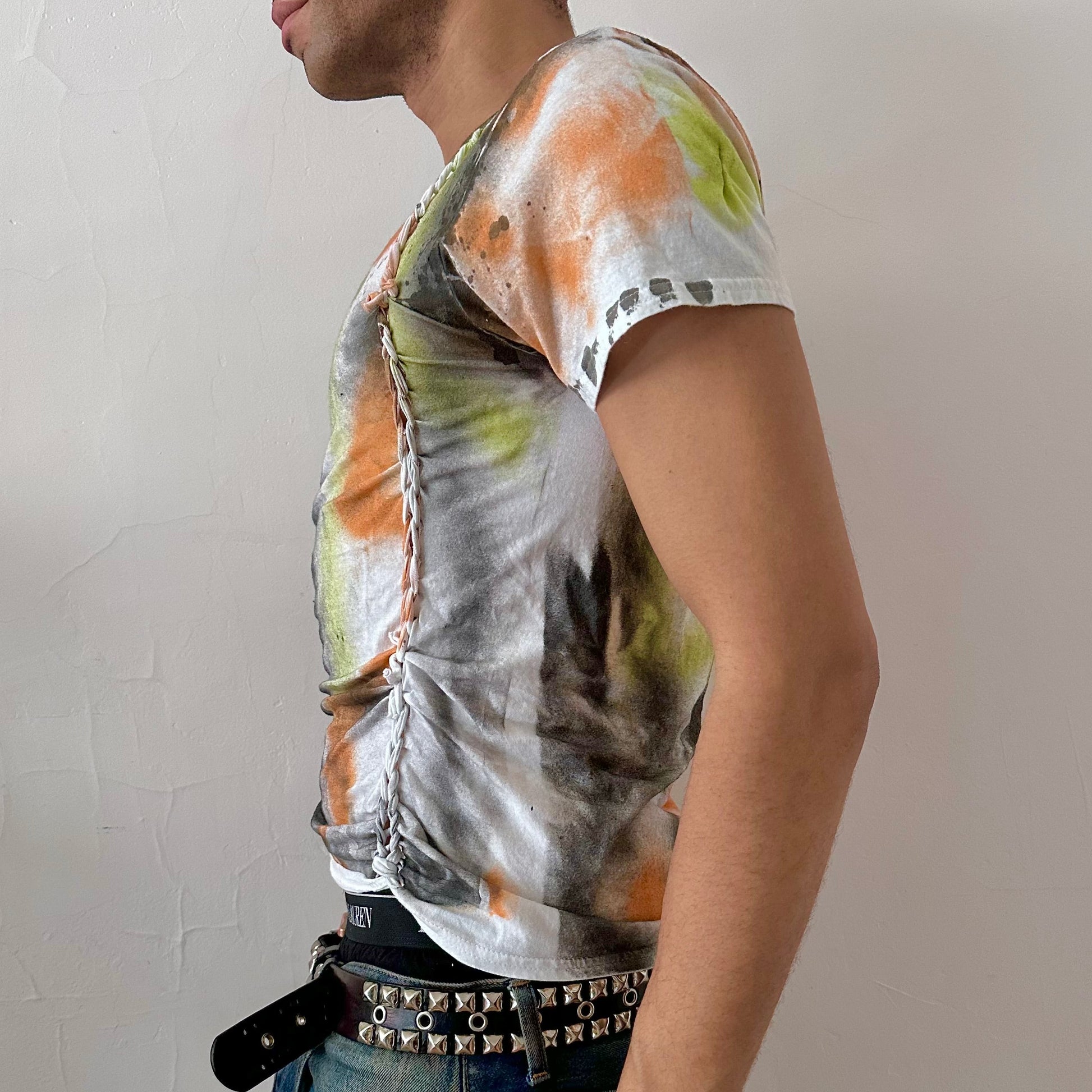Left side detail of ASTROBOI* x Gildan 'Orange Haze' showing hand-painted orange, black, and gray abstract design and braid detail on white graphic tee.