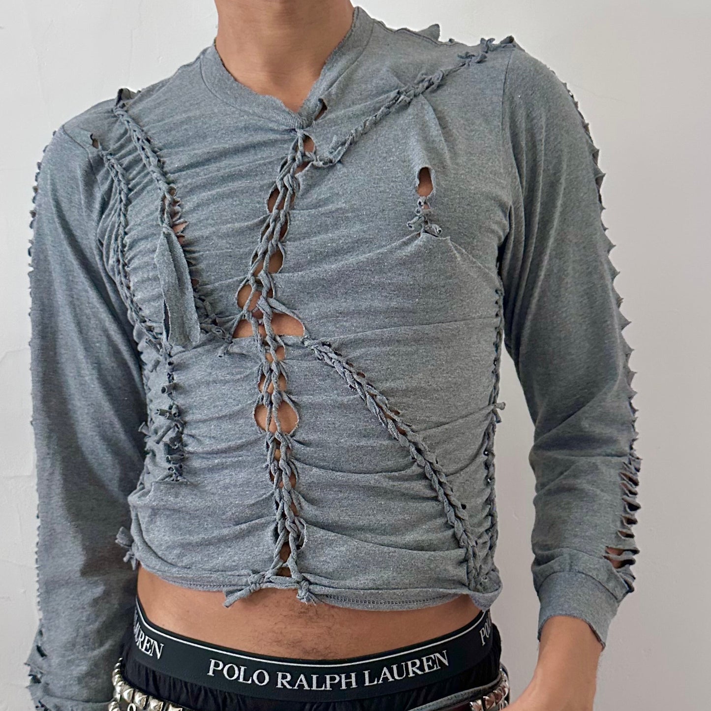 Close-up of ASTROBOI* x Gildan 'Sl8' showing hand-braided construction, knot, and cut-out detailing on heavyweight gray cotton fabric.