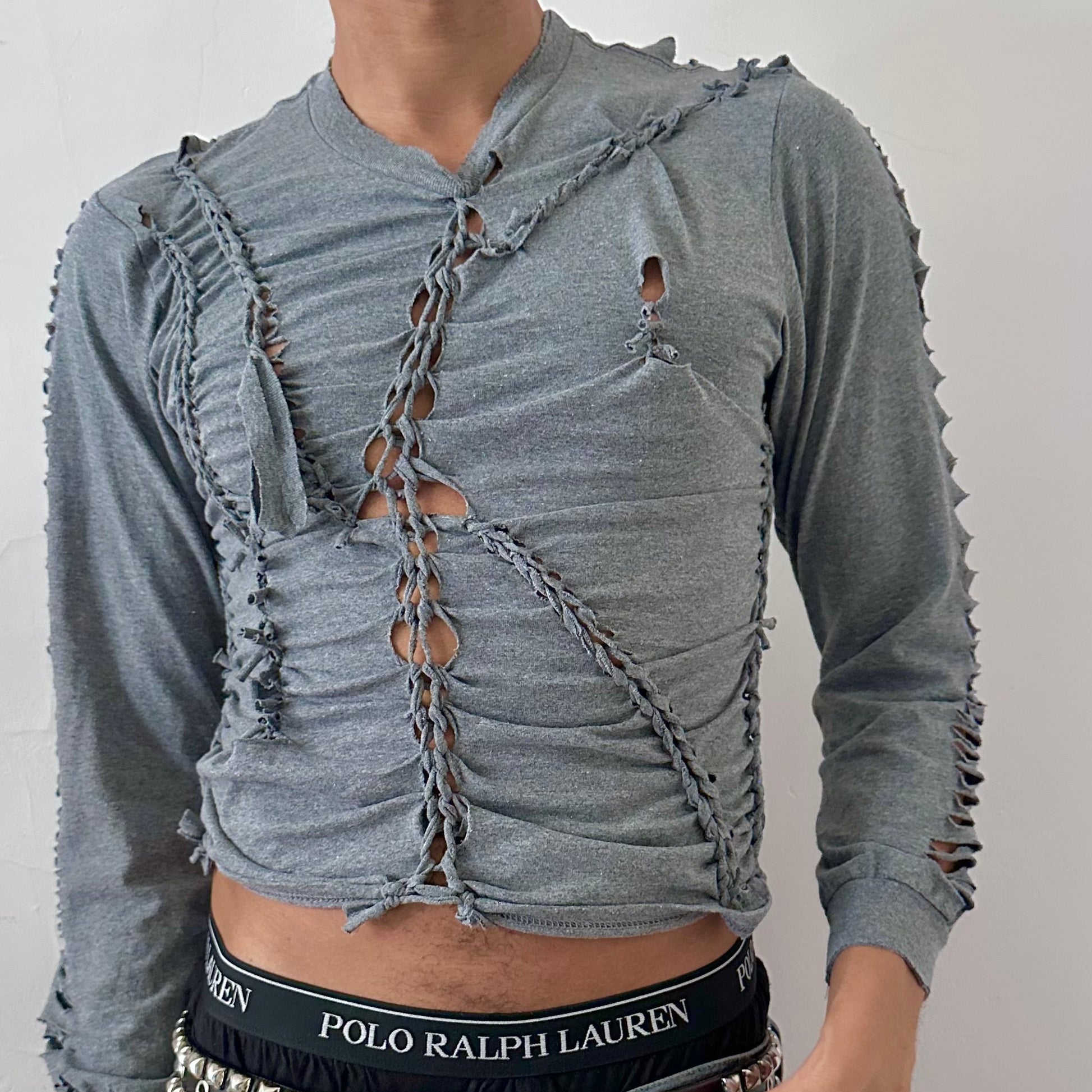 Close-up of ASTROBOI* x Gildan 'Sl8' showing hand-braided construction, knot, and cut-out detailing on heavyweight gray cotton fabric.