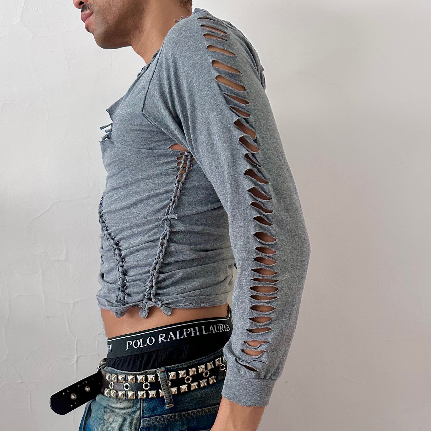 Left side detail of ASTROBOI* x Gildan 'Sl8' showing hand-braided arrangement, knot detail, and cut-outs on cropped gray long sleeve.