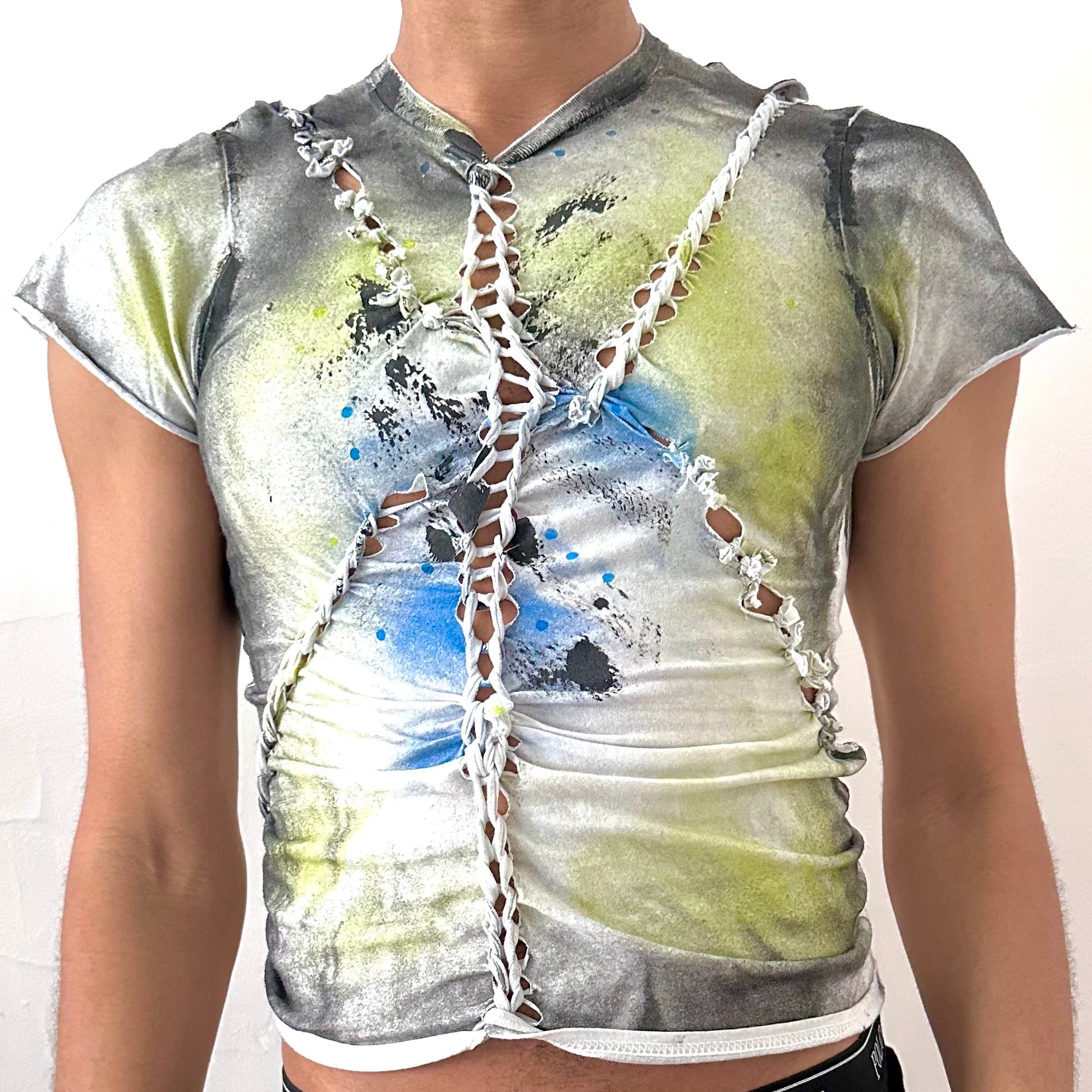 Close-up of ASTROBOI* x Gildan 'Algae' showing hand-braided construction and acid green, black, and blue abstract print on heavyweight white cotton fabric.