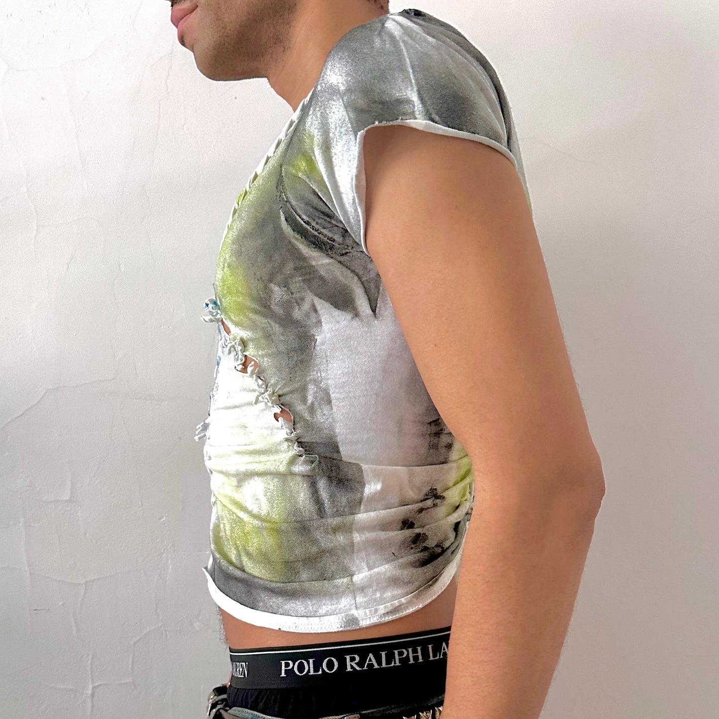 Left side detail of ASTROBOI* x Gildan 'Algae' showing hand-braided construction and acid green, black, and blue abstract print on cropped white tee.