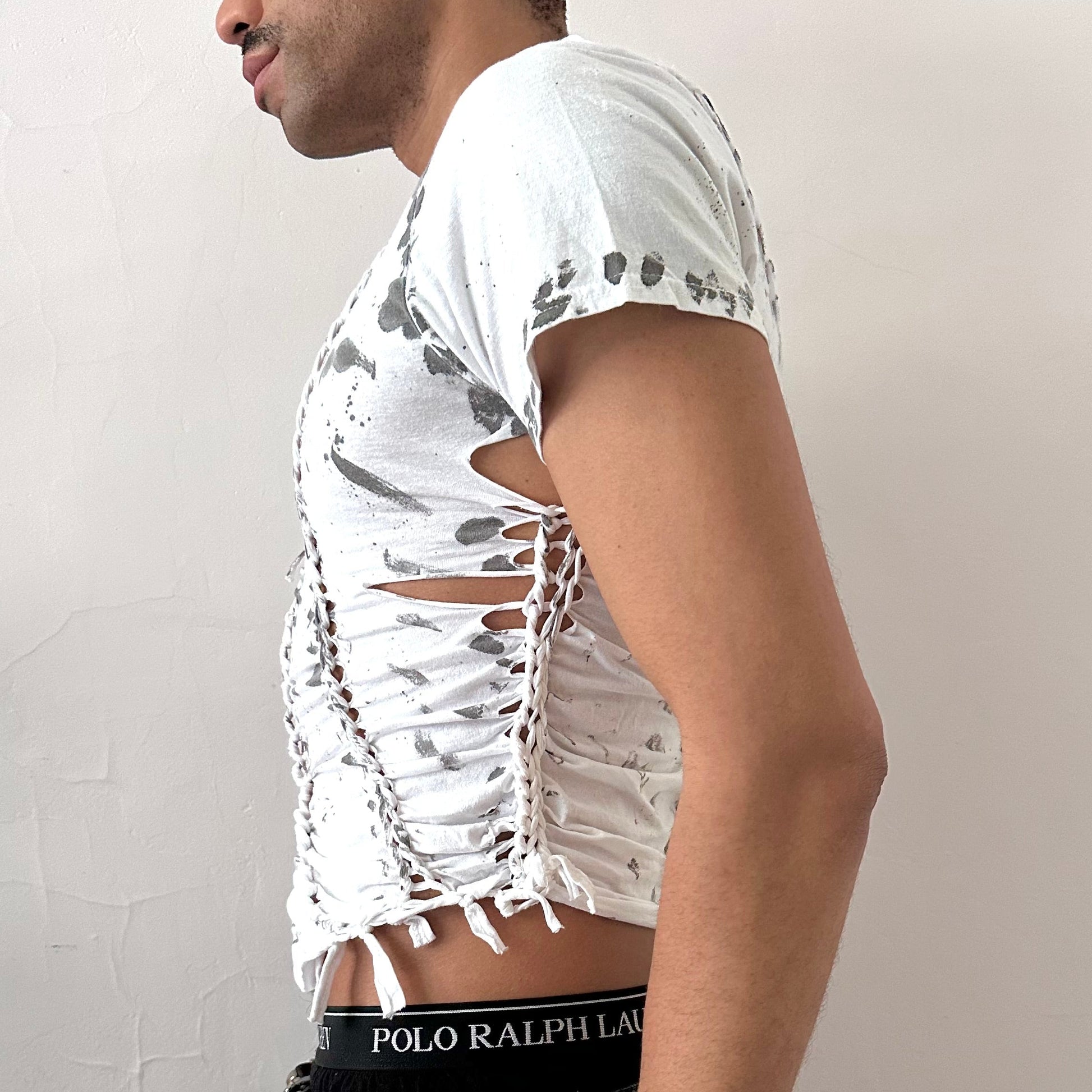 Left side detail of ASTROBOI* x Gildan '1001' showing hand-braided arrangement, cut-outs, and black painted pattern on cropped white cotton tee.