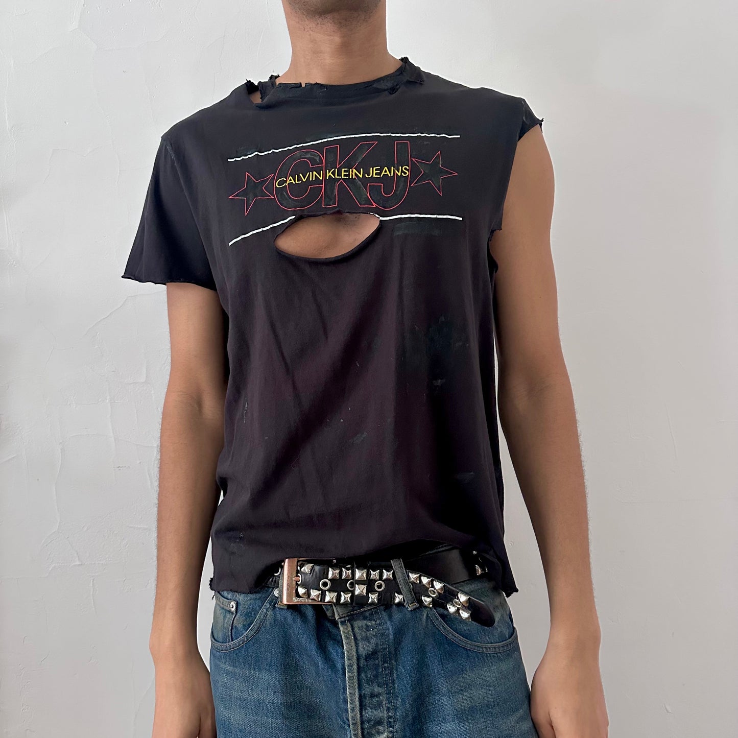 ASTROBOI* x CK Jeans black loose-fitting asymmetric logo t-shirt with CK Jeans logo across chest, asymmetric sleeves, and uneven hem, front view.