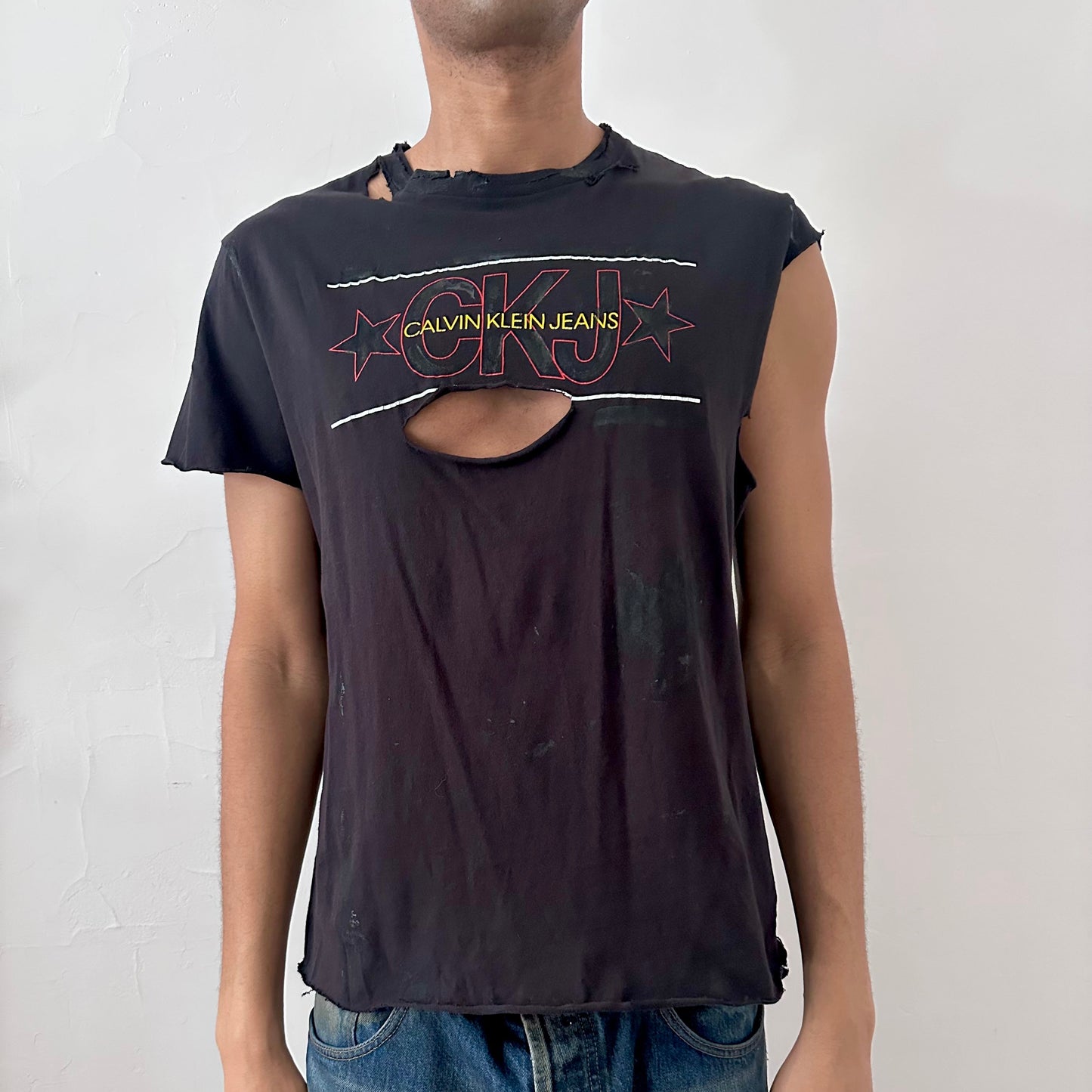 ASTROBOI* x CK Jeans black loose-fitting asymmetric logo t-shirt with CK Jeans logo across chest, asymmetric sleeves, and uneven hem, front view.