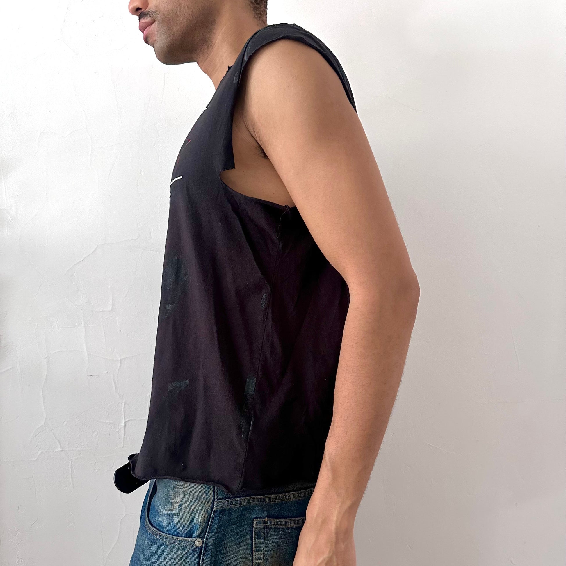 Left side detail of ASTROBOI* x CK Jeans tee showing asymmetric sleeve and uneven hem detailing on black deconstructed t-shirt.