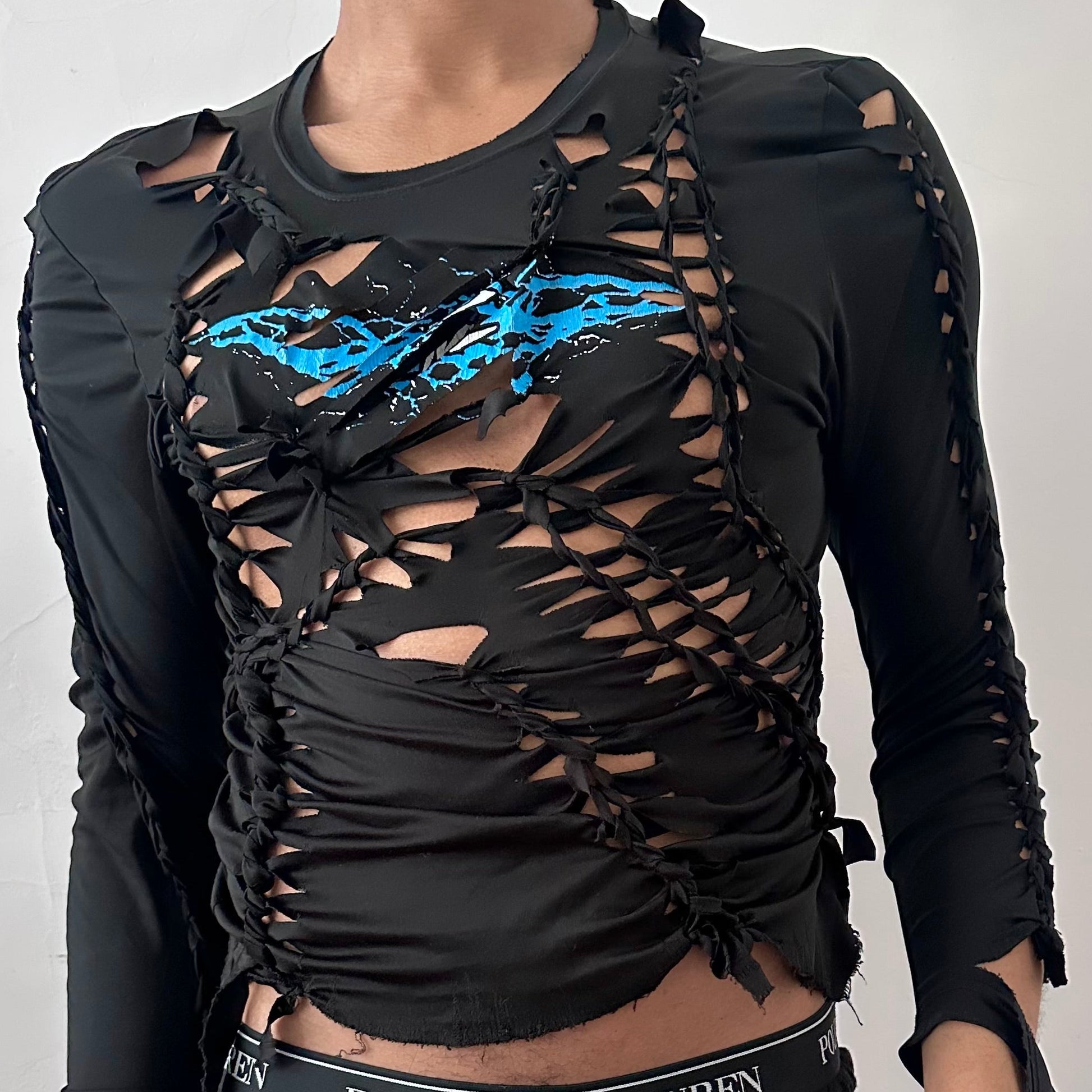 Close-up of ASTROBOI* 'Thunder' showing blue and white lightning graphic at center chest, hand-braided construction, and cut-out detailing on black stretch Lycra fabric.