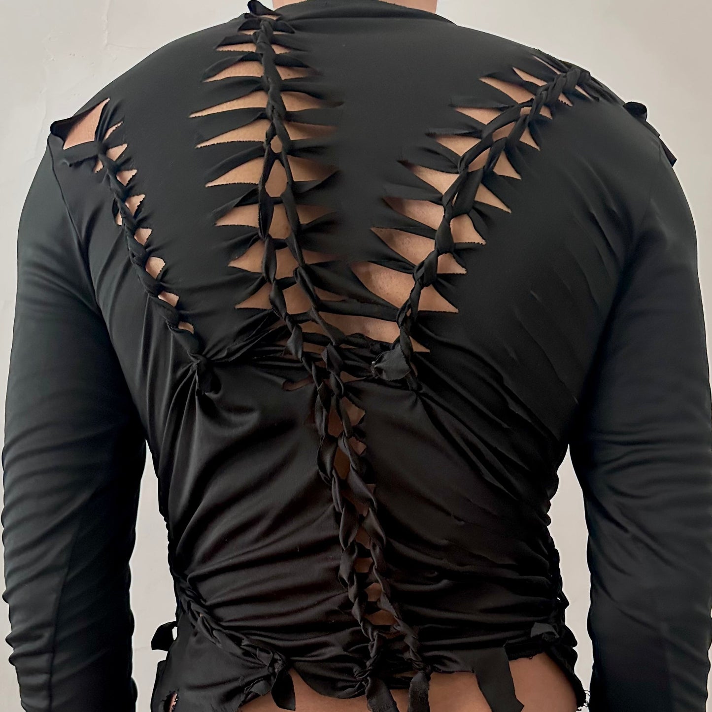 ASTROBOI* 'Thunder' black braided compression top, rear view close up showing braid, cut-out, and raw hem construction, worn by male model.