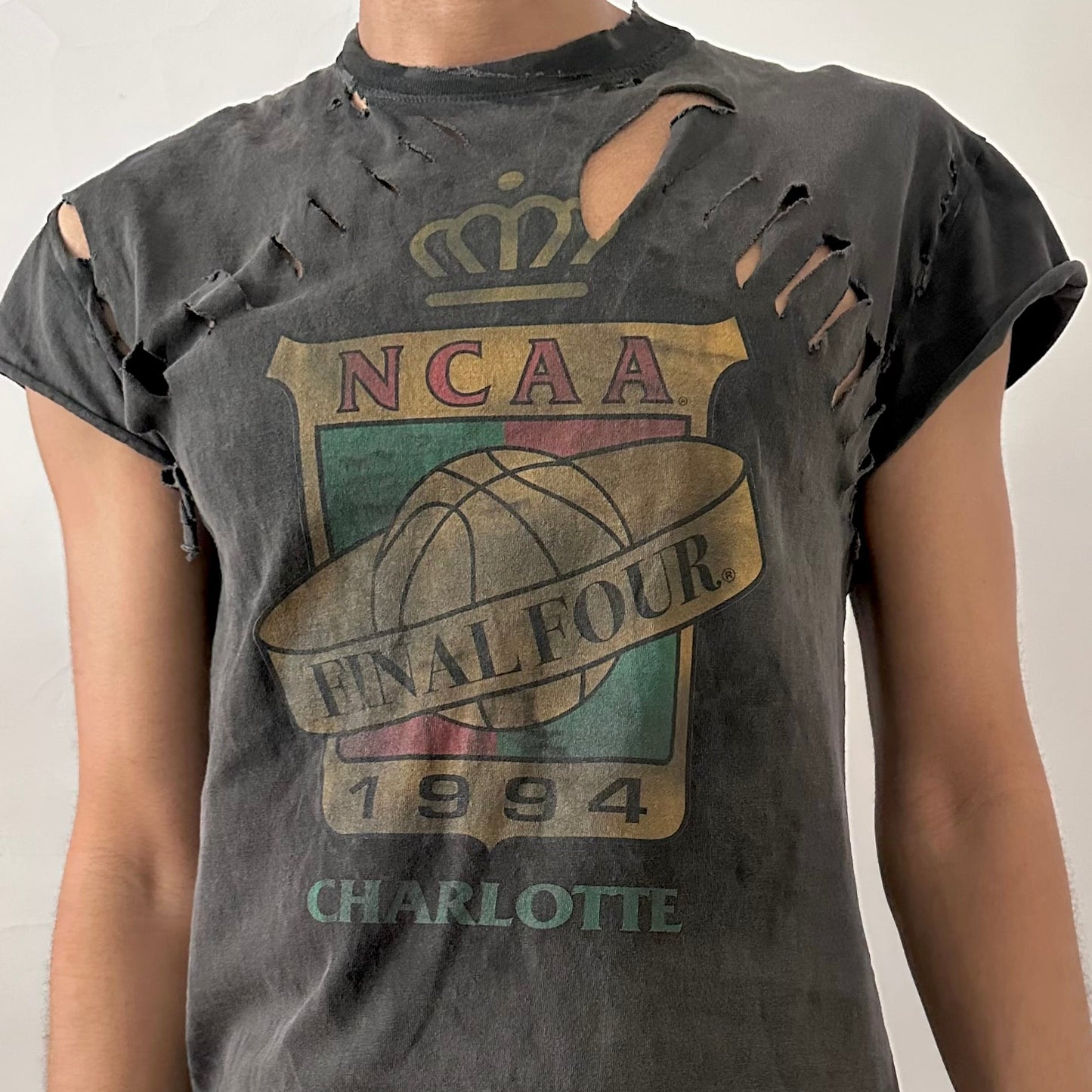 Close-up of ASTROBOI* NCAA Basketball tank showing muted chest graphic, distressed holes, and raw edge detailing on black cotton fabric.