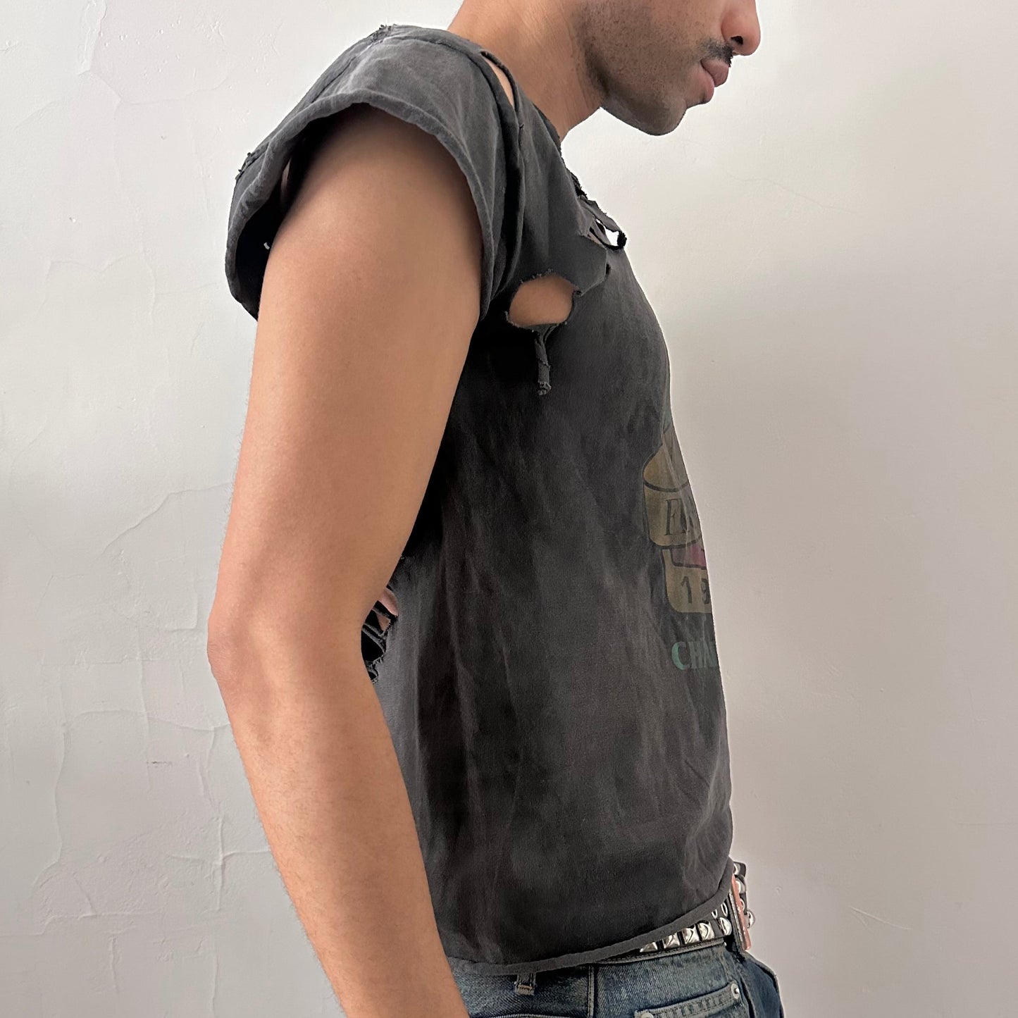Right side detail of ASTROBOI* NCAA Basketball tank showing distressed holes and raw edge construction on loose-fitting black cotton base.