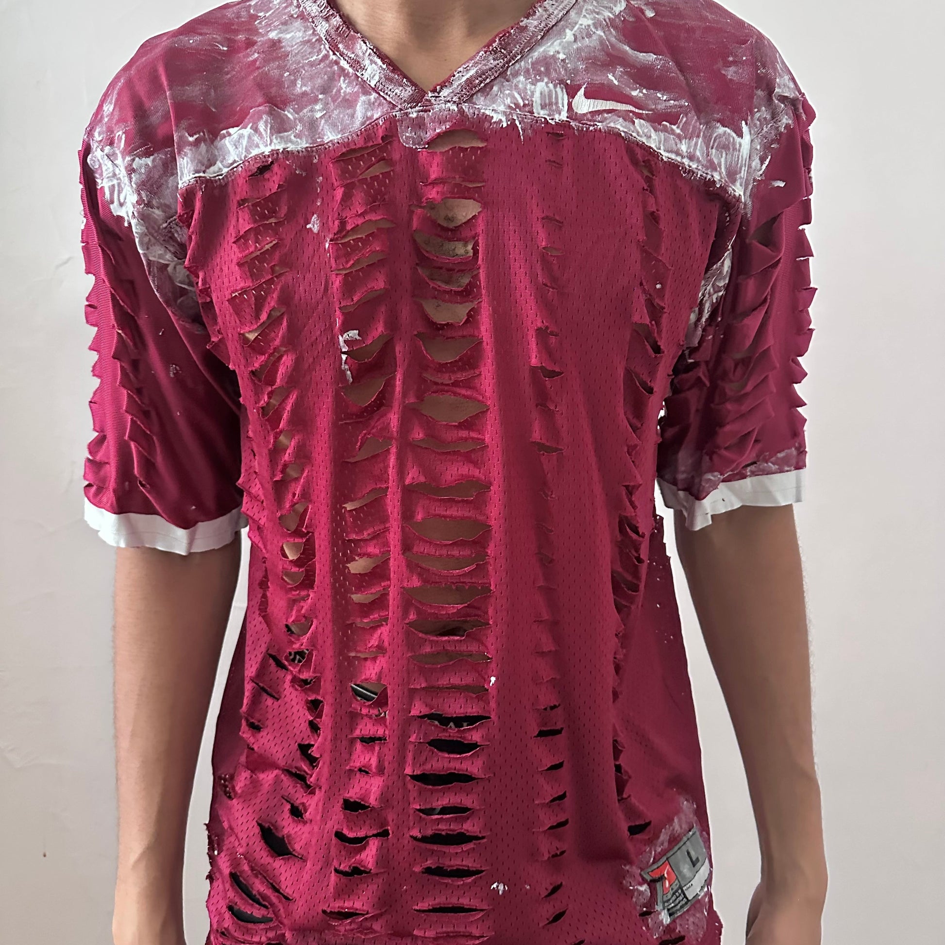  Close-up of ASTROBOI* x Nike 'BloodThirst' showing white painterly detail on breathable maroon mesh fabric and raw hem finish.