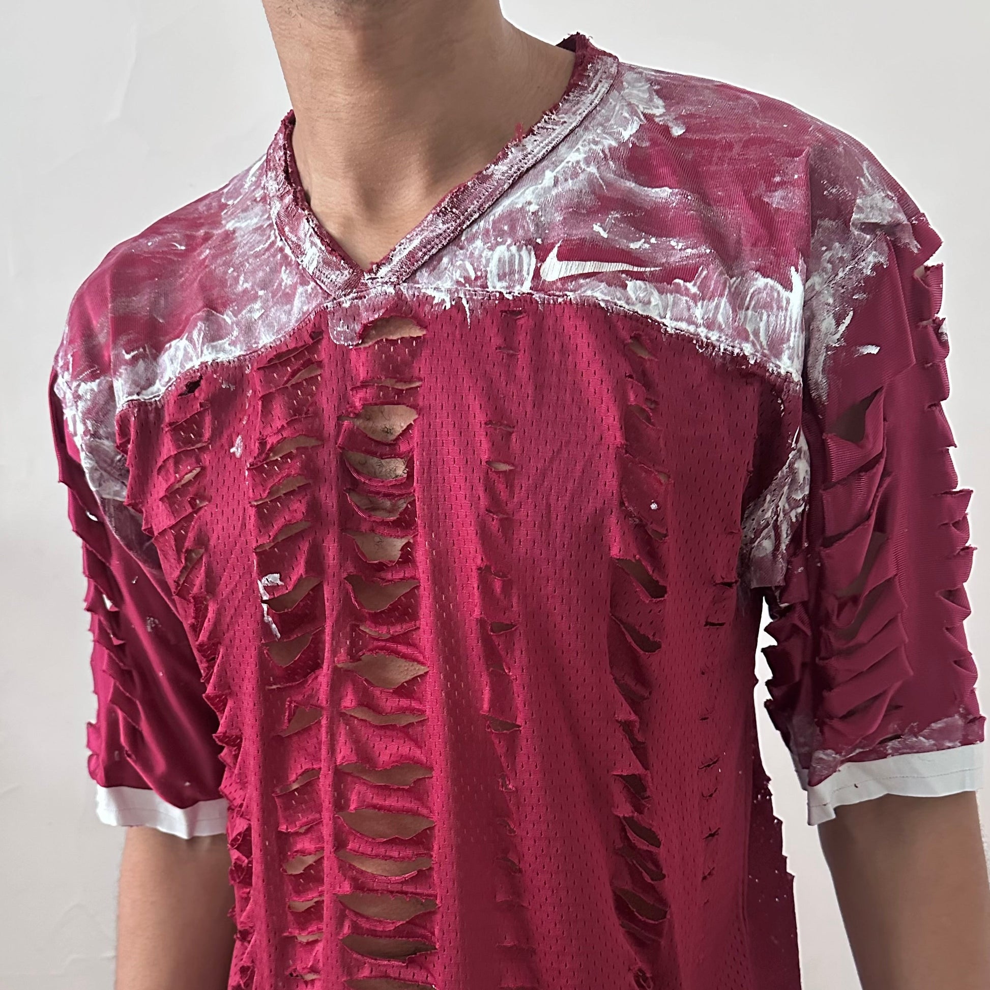 Close-up of ASTROBOI* x Nike 'BloodThirst' showing white painterly detail on breathable maroon mesh fabric and raw hem finish.