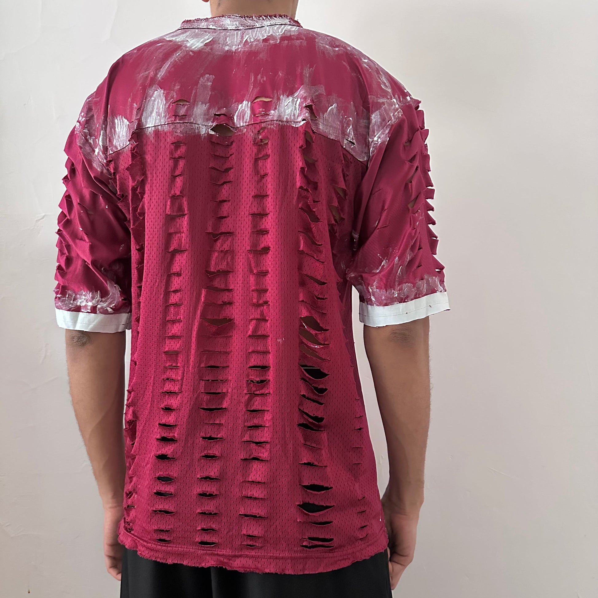 ASTROBOI* x Nike 'BloodThirst' maroon mesh painterly jersey, rear view showing white painterly detail and raw hem construction, worn by male model.