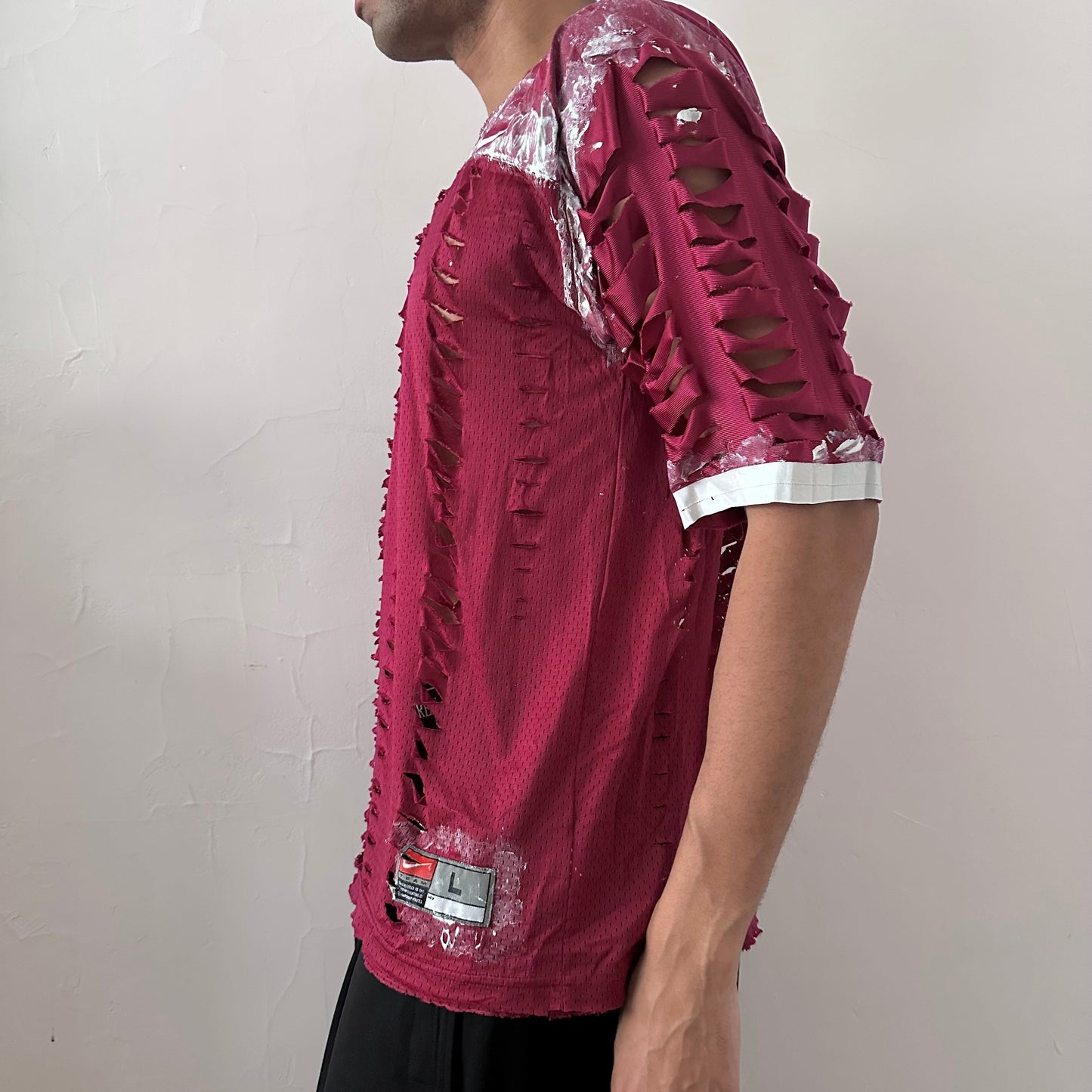 Left side detail of ASTROBOI* x Nike 'BloodThirst' showing hand-applied white paint detail on maroon mesh fabric and raw hem finish.