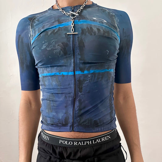 ASTROBOI* x Oakley blue painted cycling jersey with white and black painterly pattern, zipper closure, and Oakley logo at right chest, slim fitting, front view.