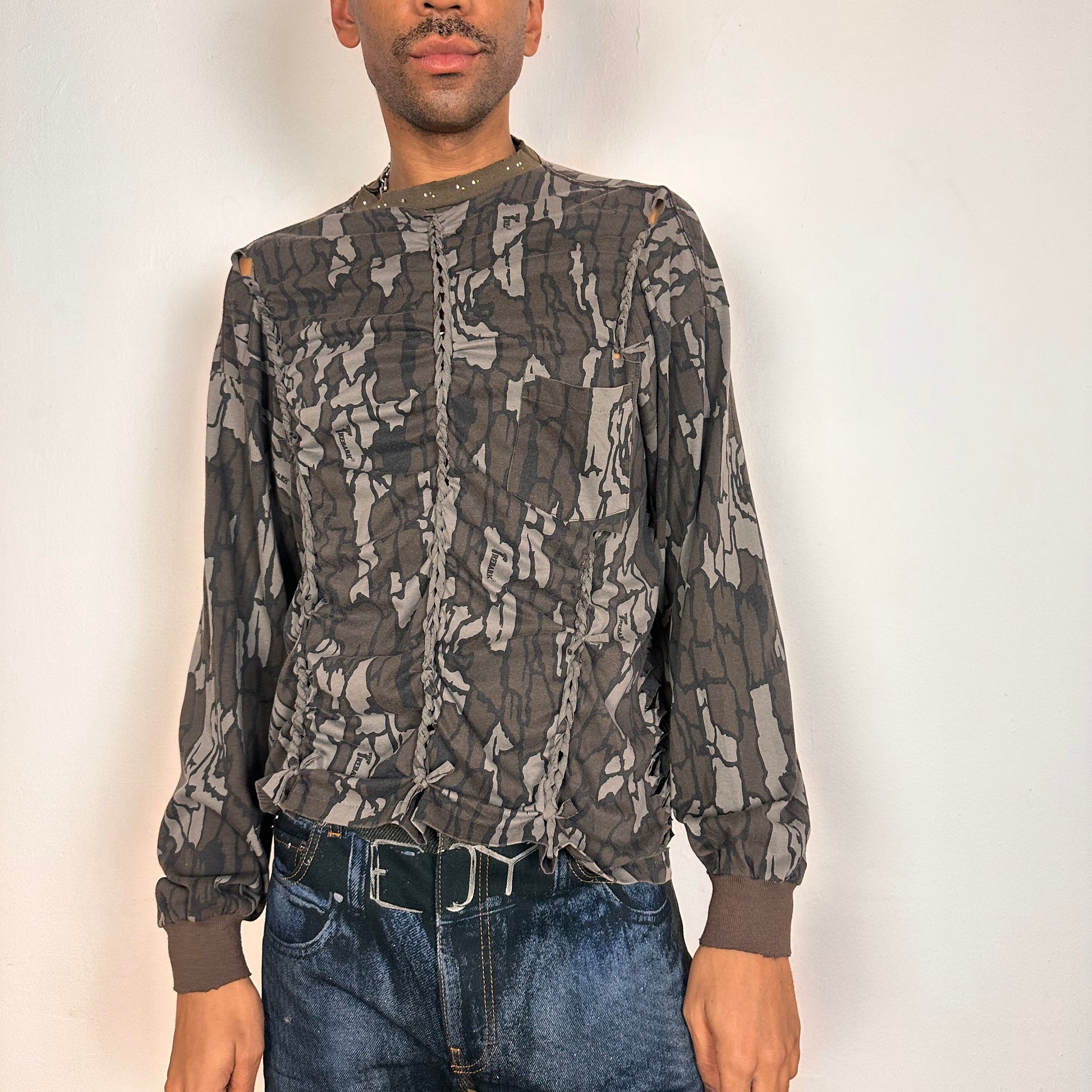 Front of ASTROBOI* gray camouflage long sleeve T-shirt with braided torso detailing, rhinestone neckline, raw hem, and chest pocket, handmade in NYC.