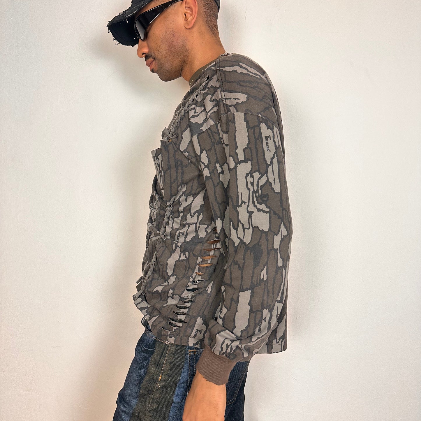Left of ASTROBOI* gray camouflage long sleeve T-shirt with braided torso detailing, rhinestone neckline, raw hem, and chest pocket, handmade in NYC.