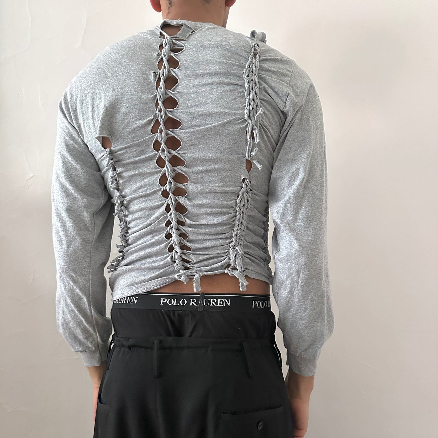 ASTROBOI* x Gildan 'Neutral' gray braided twist long sleeve t-shirt, rear view showing braid, knot, and cut-out construction, worn by male model.