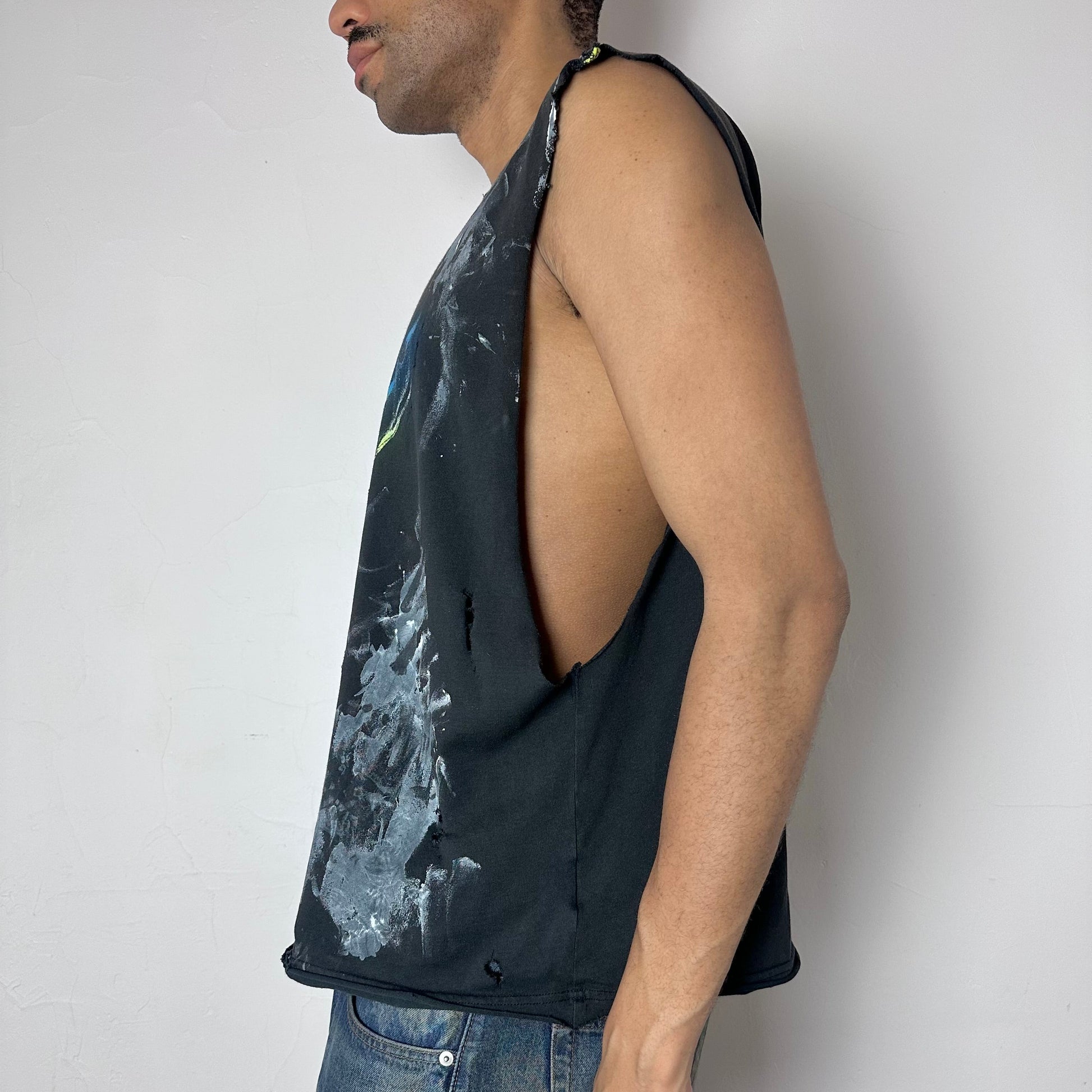Left side detail of ASTROBOI* x Nike 'Celestial' showing painterly brushstroke detail and raw hem construction on navy muscle shirt.