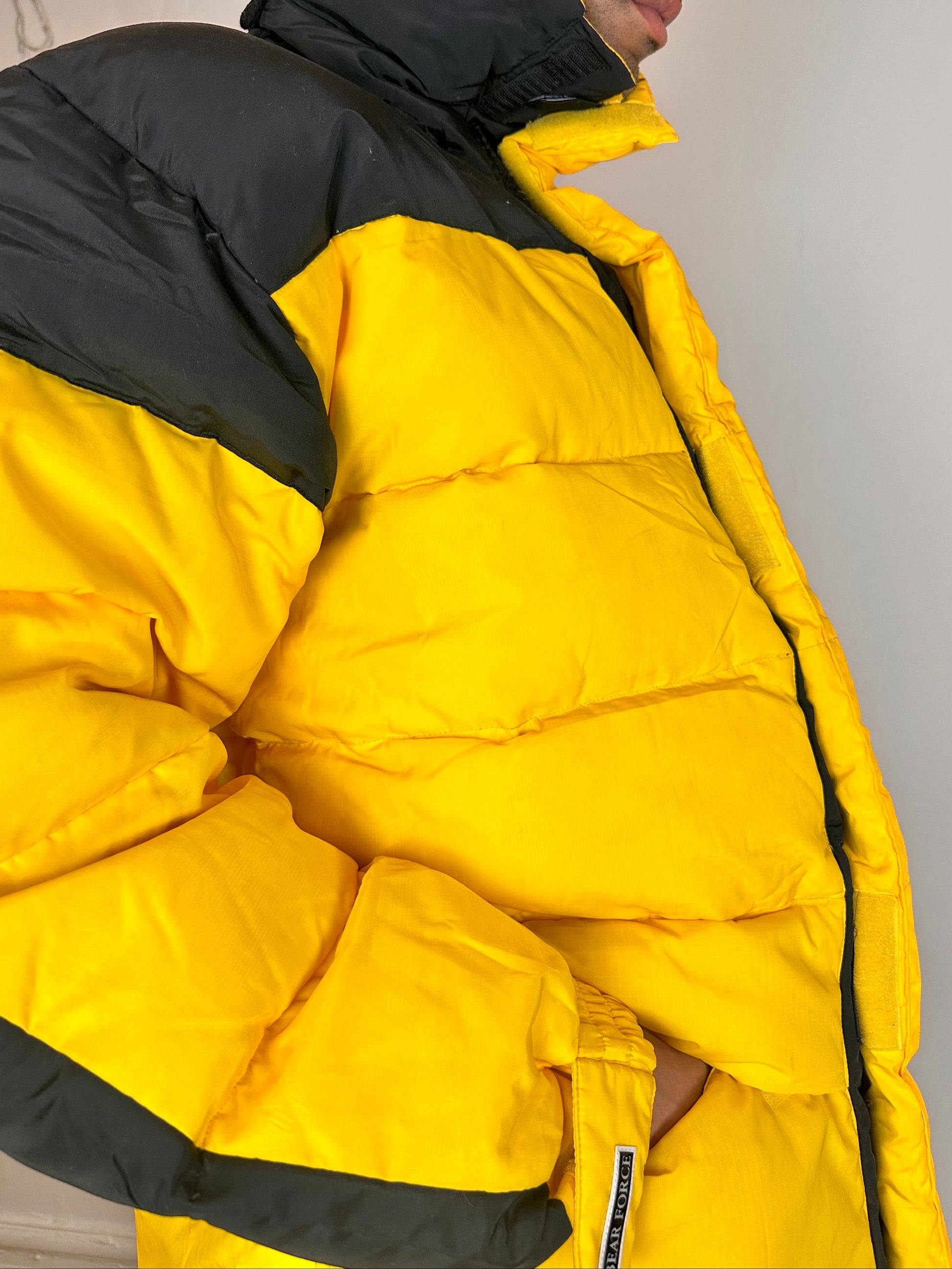 Right side detail on Bear Mountain yellow puffer jacket with oversized architectural fit, chest logo detail, super warm insulation, size XL.