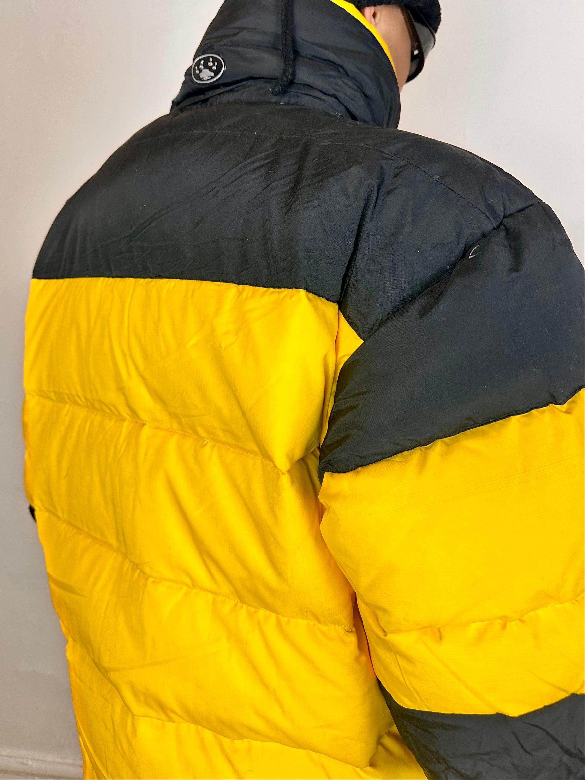 Back detail on Bear Mountain yellow puffer jacket with oversized architectural fit, chest logo detail, super warm insulation, size XL.