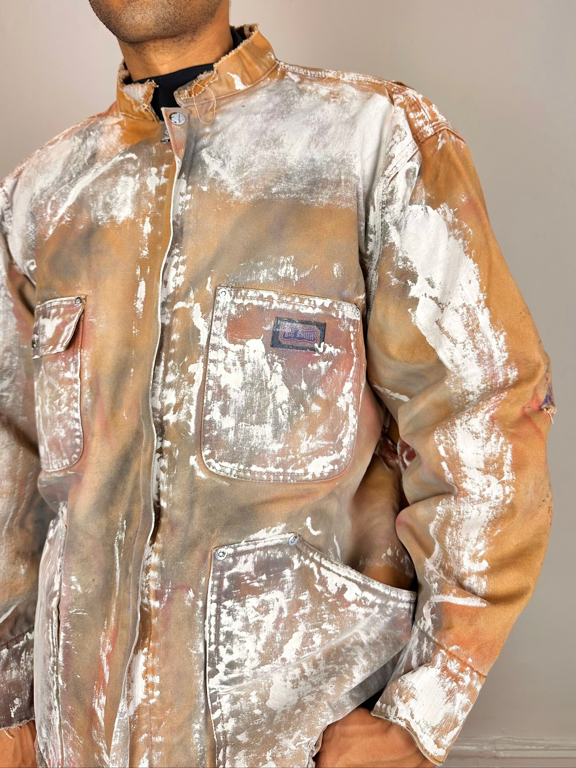 Close up of ASTROBOI* Big Smith tan workwear jacket with quilted lining, boxy fit, deconstructed collar, and black red white paint detailing, size XL.