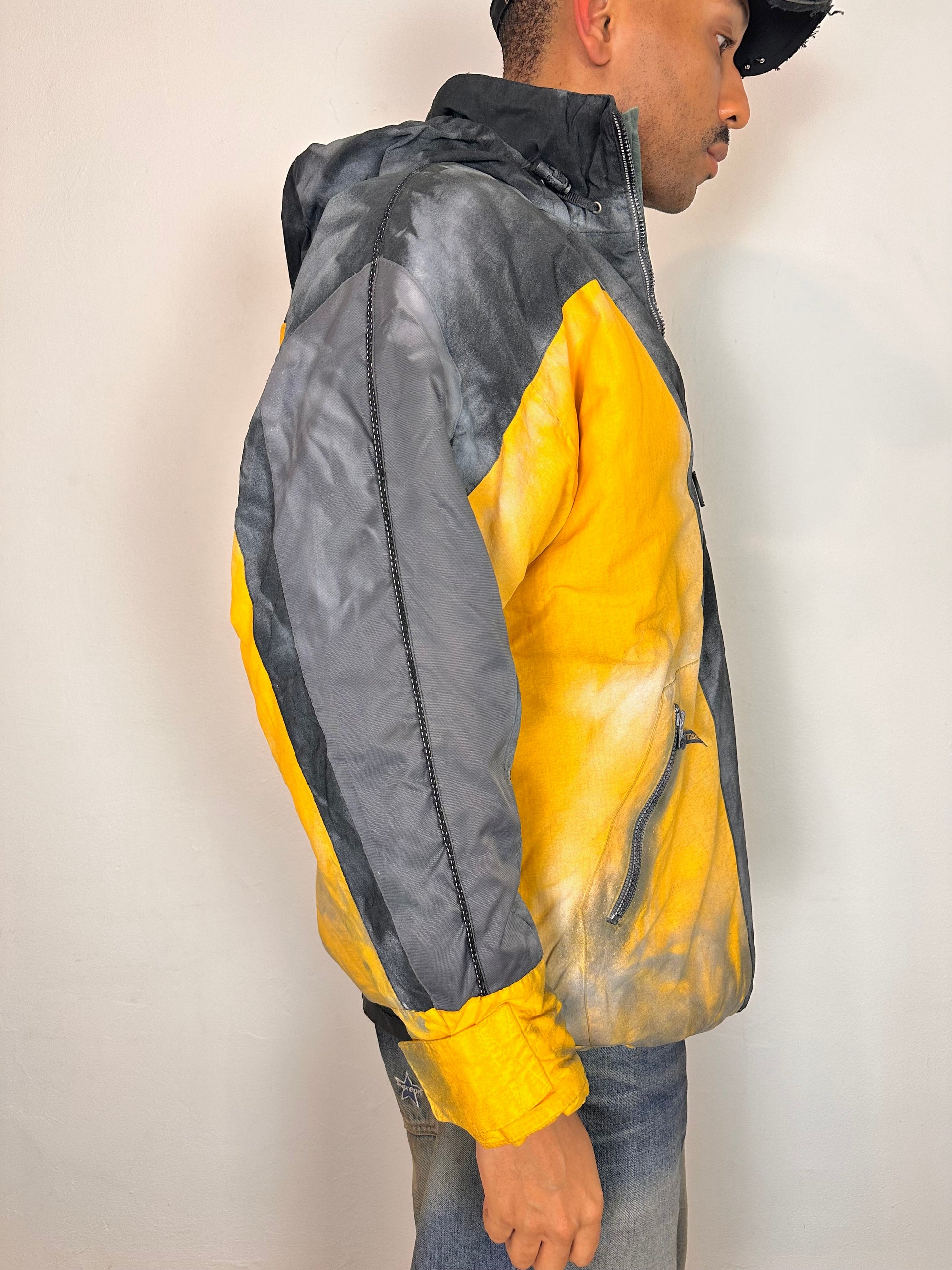 Right side of ASTROBOI* x Starter yellow and black airbrushed puffer jacket with grey sleeves, reflective taping, and adjustable toggles, men’s XL.