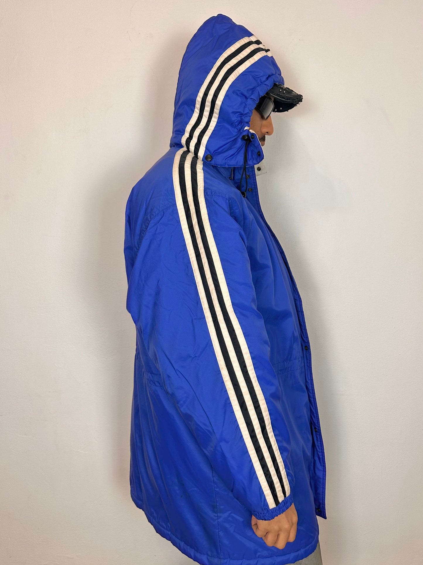 Right side of Vintage Adidas blue oversized winter puffer coat with detachable hood, white stripes, and long insulated silhouette, size XXL.