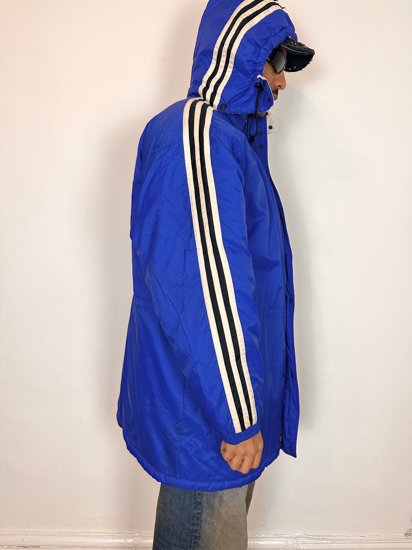 Right side of Vintage Adidas blue oversized winter puffer coat with detachable hood, white stripes, and long insulated silhouette, size XXL.