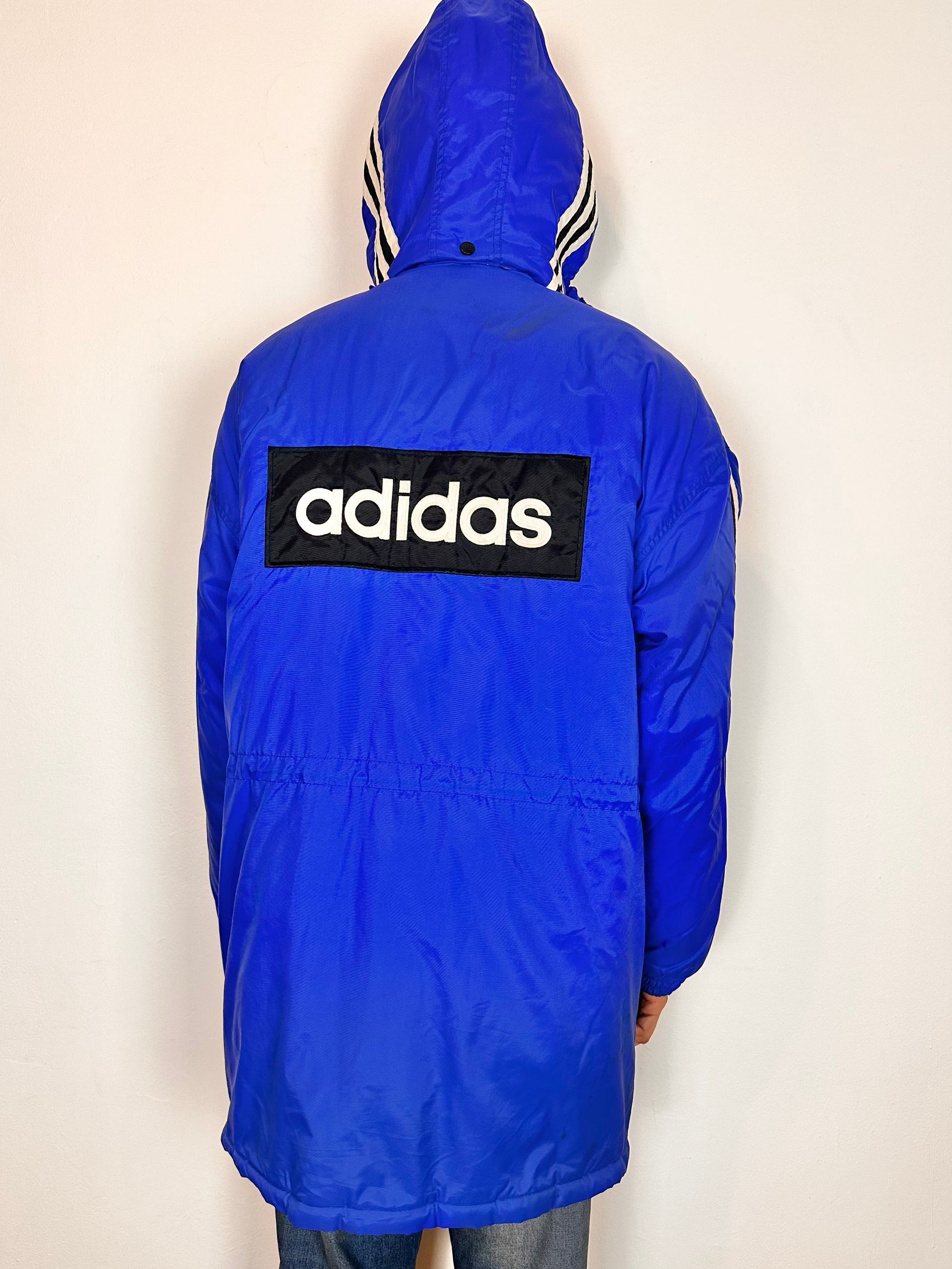Back of Vintage Adidas blue oversized winter puffer coat with detachable hood, white stripes, and long insulated silhouette, size XXL.