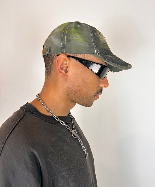 Right side of “Green and brown distressed ASTROBOI* Hawaii hat with rhinestones, metallic paint, and sterling-steel piercings, customized in NYC.”