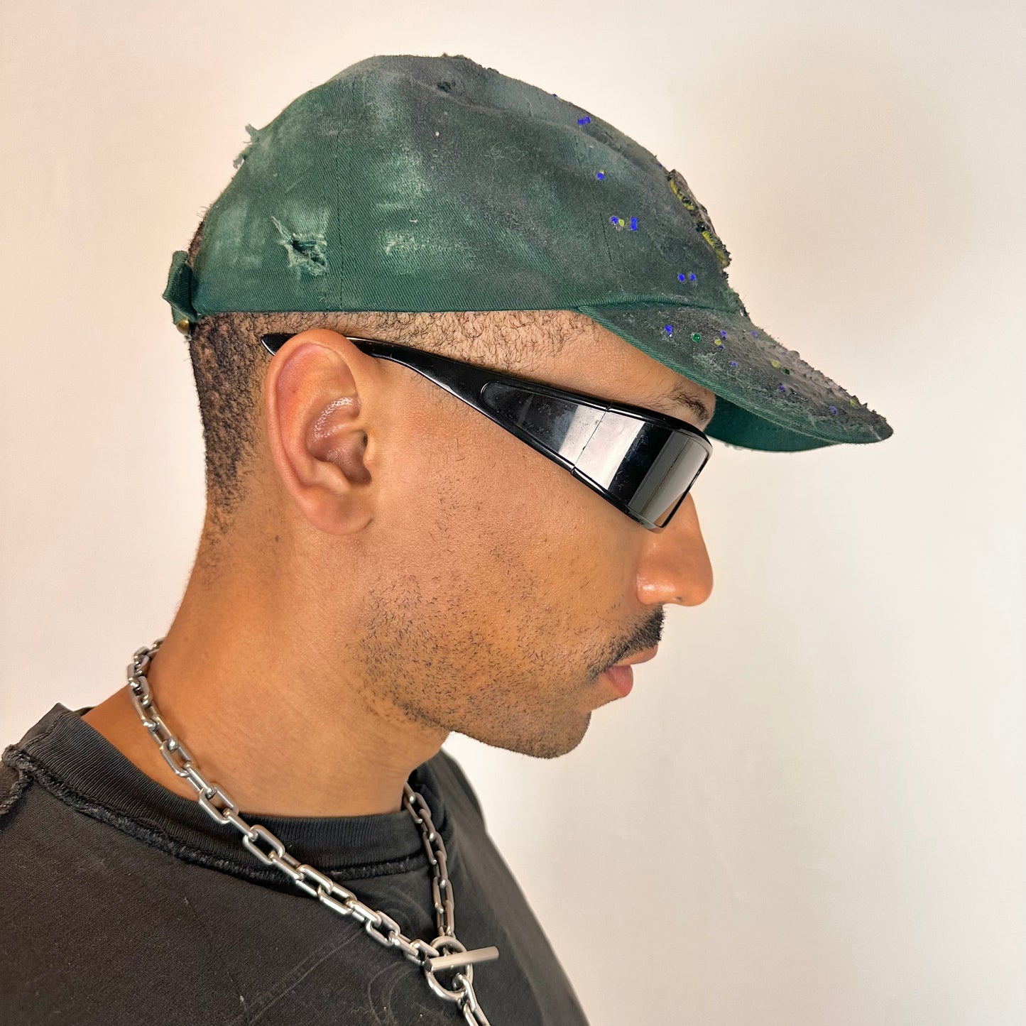 Right side of ASTROBOI* green 818 baseball cap with blue rhinestones, black resin slime effect, airbrushed paint details, light distressing, and an adjustable back strap.