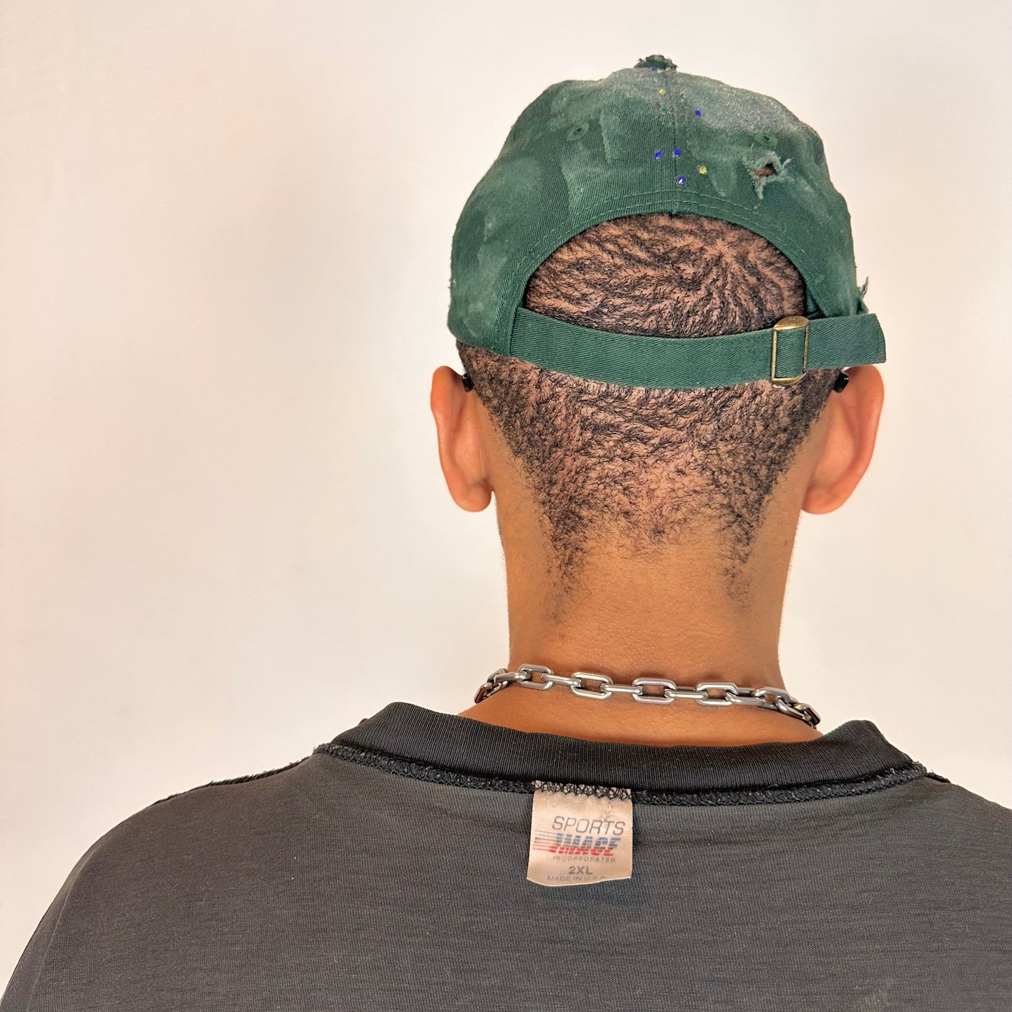 Back of ASTROBOI* green 818 baseball cap with blue rhinestones, black resin slime effect, airbrushed paint details, light distressing, and an adjustable back strap.