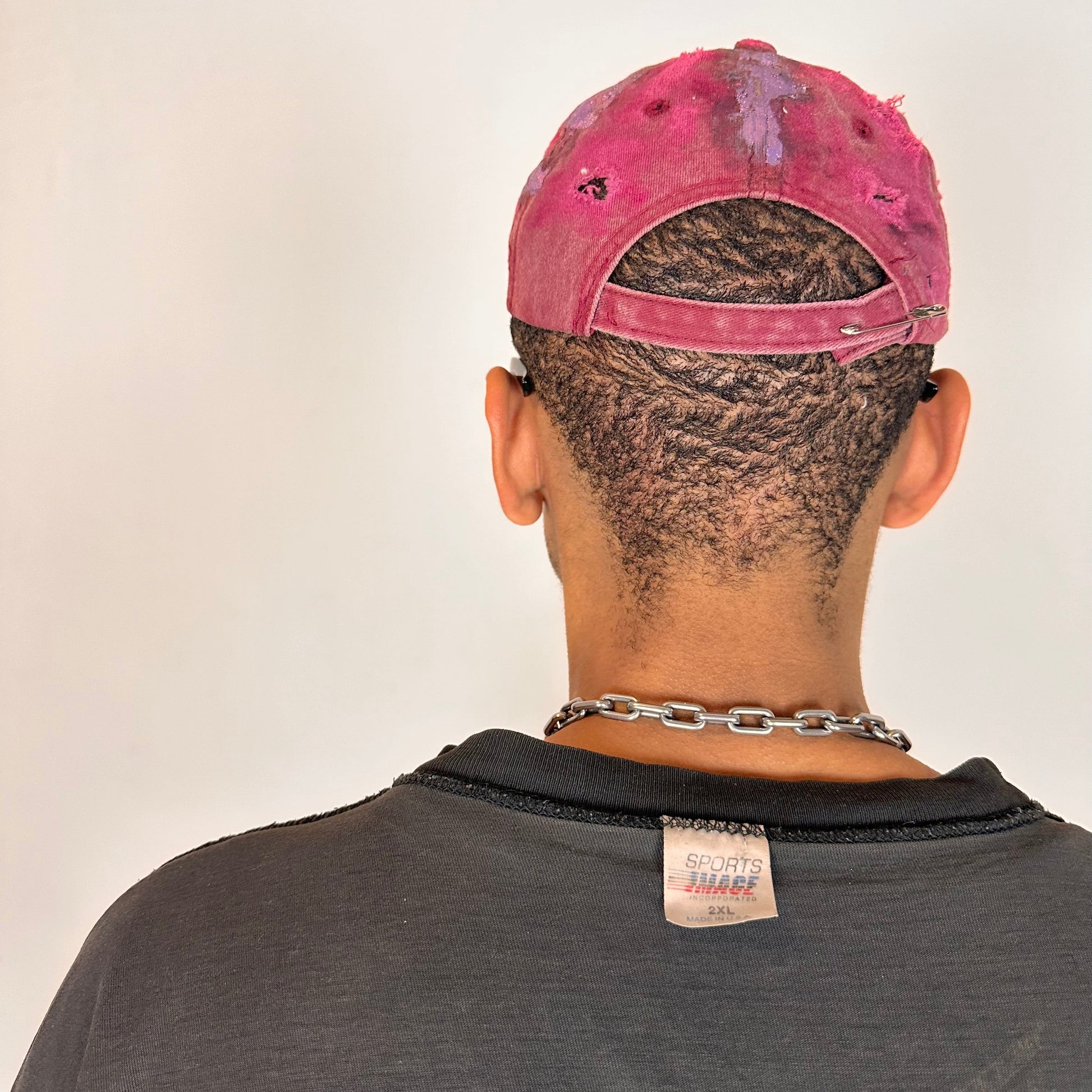 Back of ASTROBOI* MARS distressed metallic cap with lavender paint accents, bent visor, and safety pin adjustment detail.