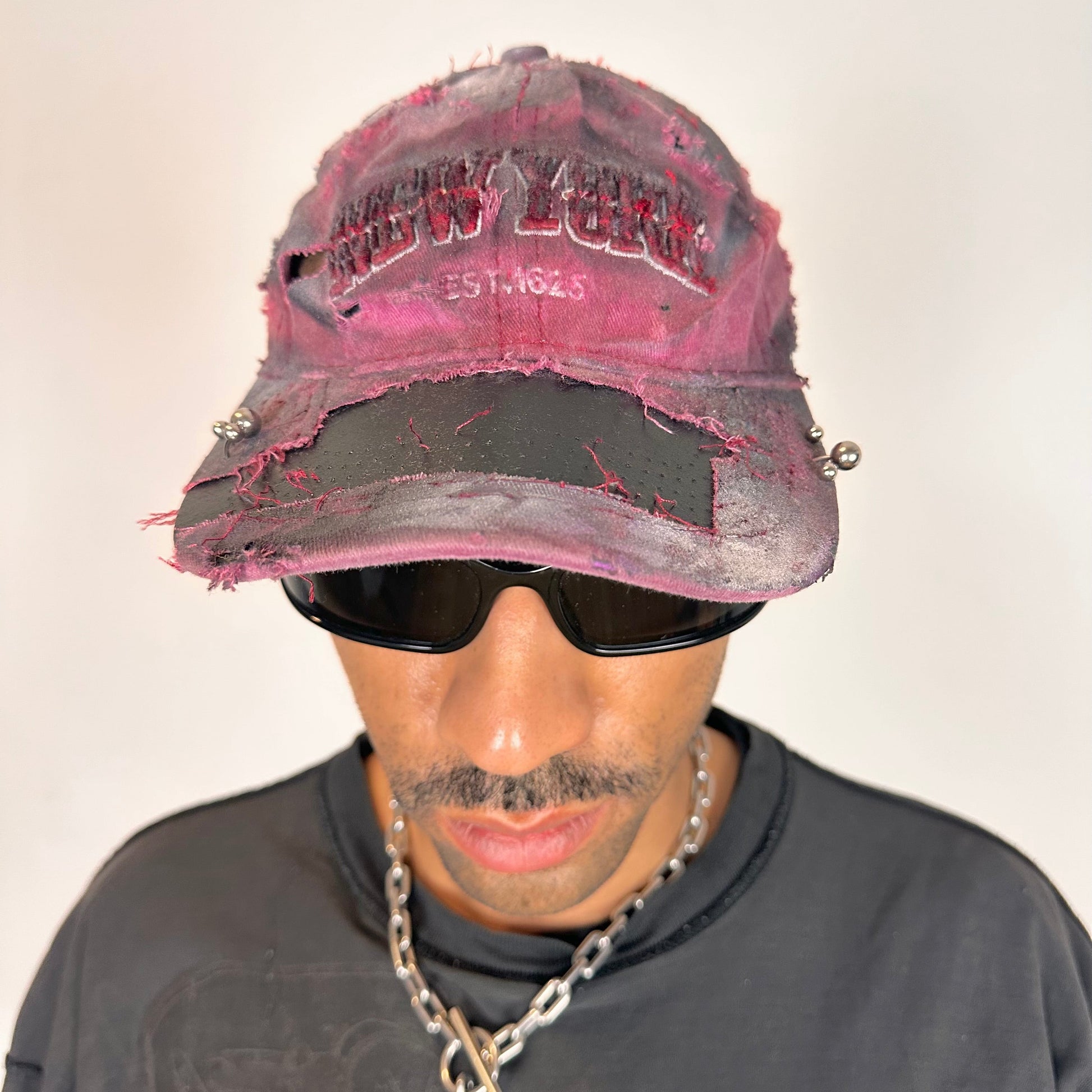 Front of ASTROBOI* Burn Out red New York hat with distressed finish, white and black paint details, and stainless steel piercings, adjustable back strap.