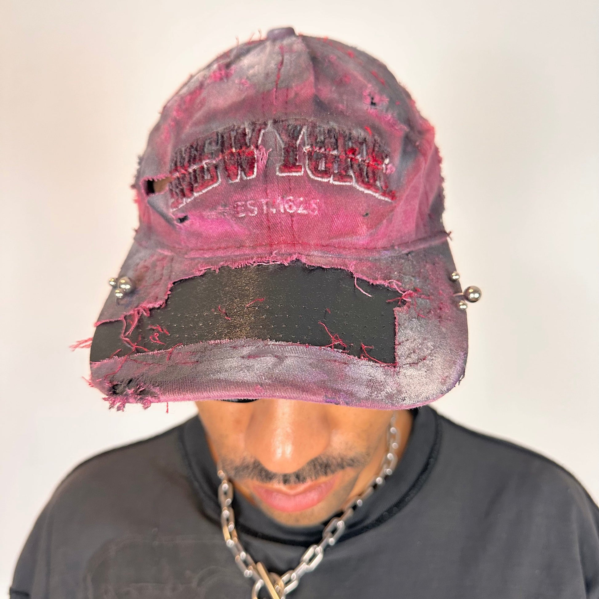 Front of ASTROBOI* Burn Out red New York hat with distressed finish, white and black paint details, and stainless steel piercings, adjustable back strap.