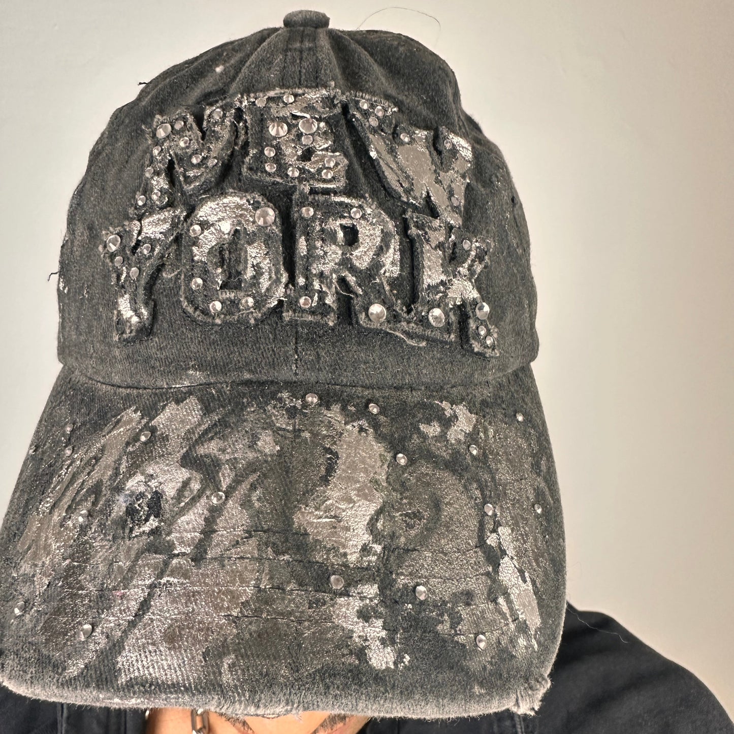 Cover image of ASTROBOI* chrome New York baseball cap with metallic silver paint, rhinestone logo lettering, distressed finish, and rhinestone visor detailing