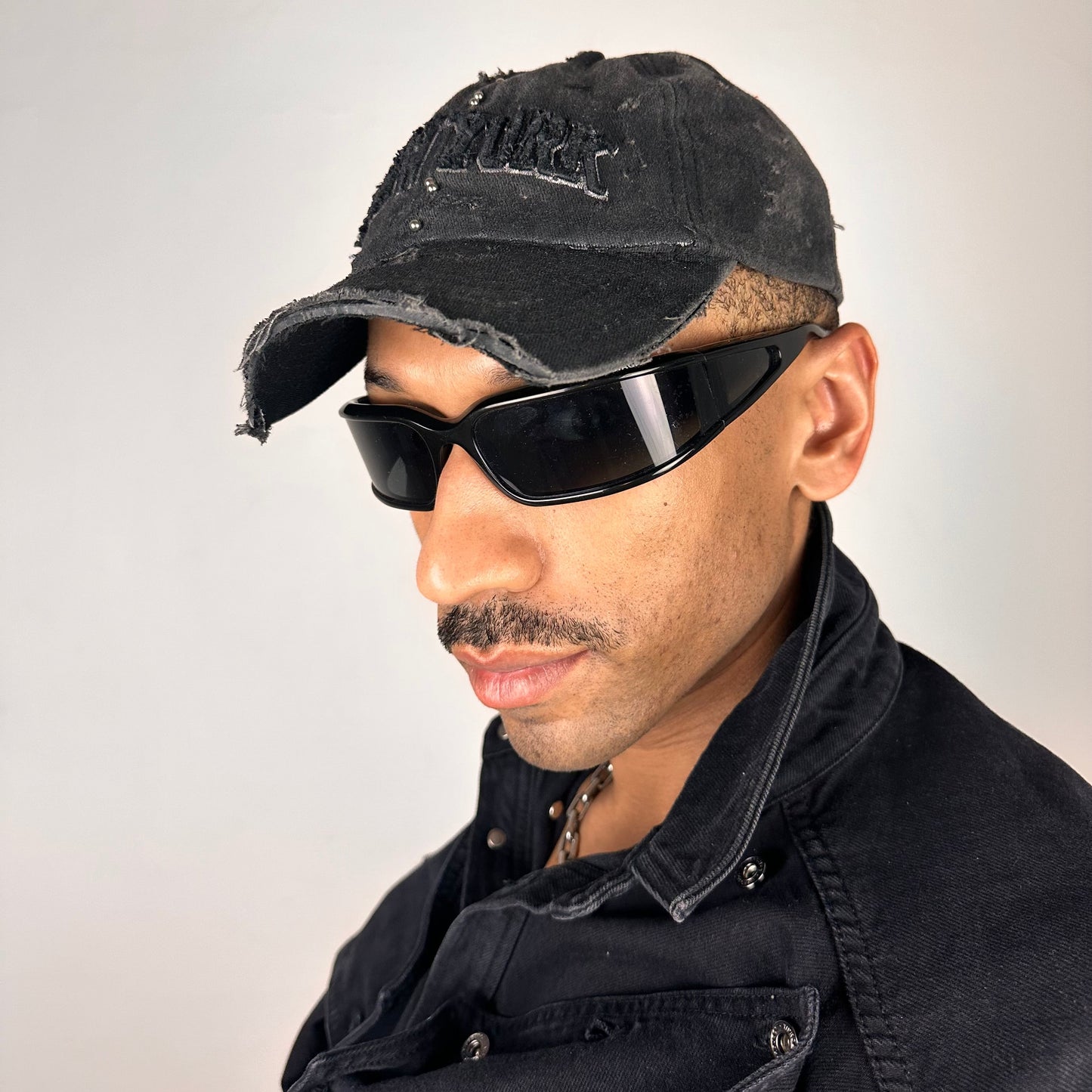 Visor detail on ASTROBOI* 'Kinky' New York Black Distressed Pierced Half Visor Hat - flat detail 