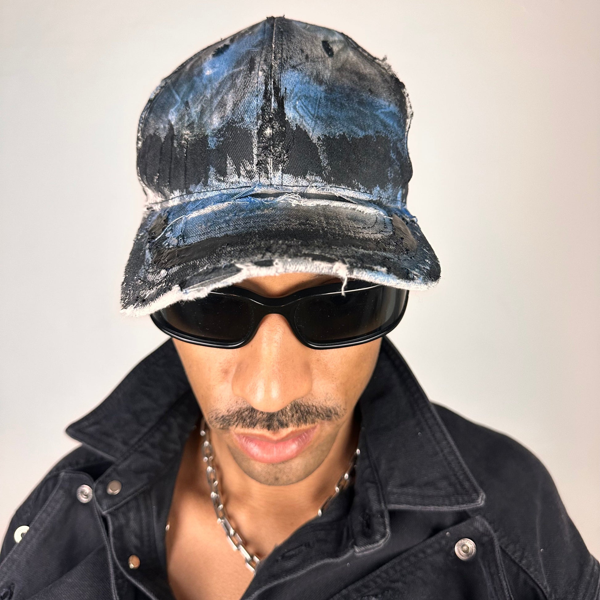 Overview of ASTROBOI* white trompe l’oeil denim print hat with blue and black paint, resin accents, and distressed detailing.