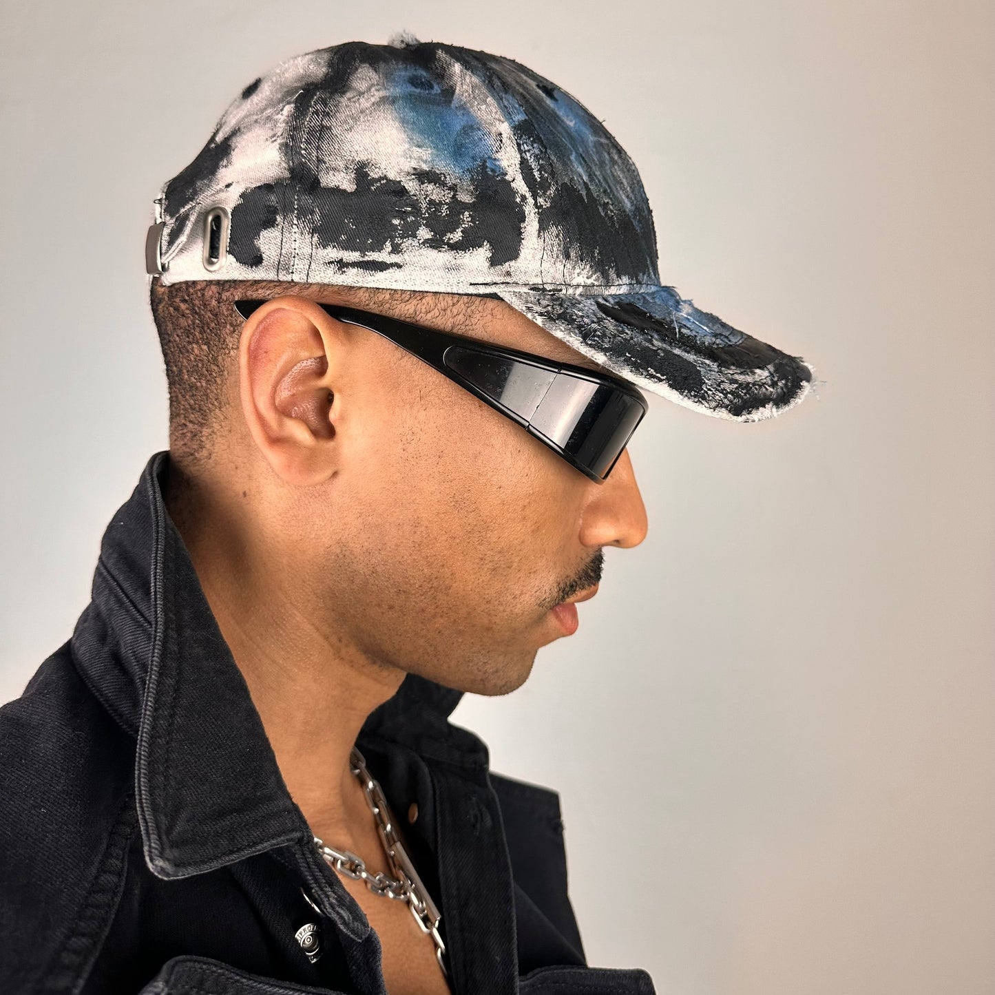 Right side of ASTROBOI* white trompe l’oeil denim print hat with blue and black paint, resin accents, and distressed detailing.